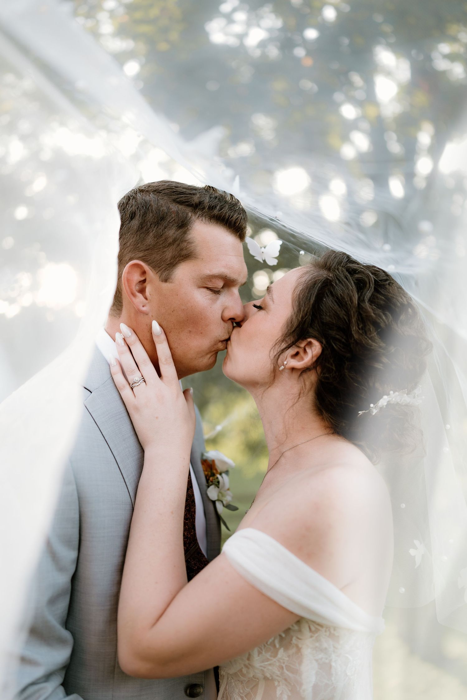 A romantic kiss between newlyweds with a dreamy sunlit background.
