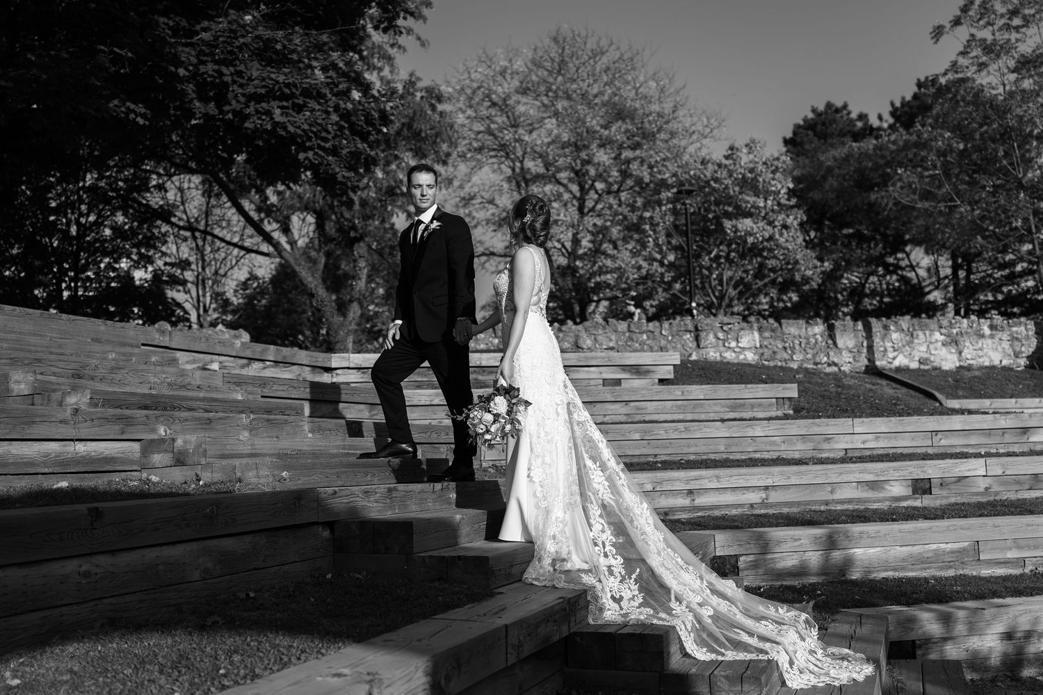 Black and white wedding photos showing couple walking along stone steps outdoors.