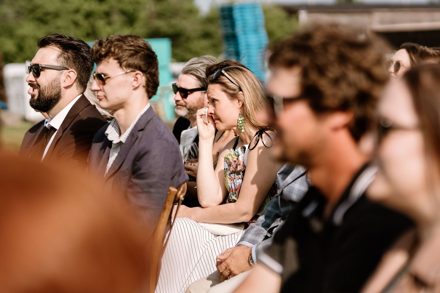 Wedding guests seated in rows of wooden chairs at an outdoor ceremony venue.