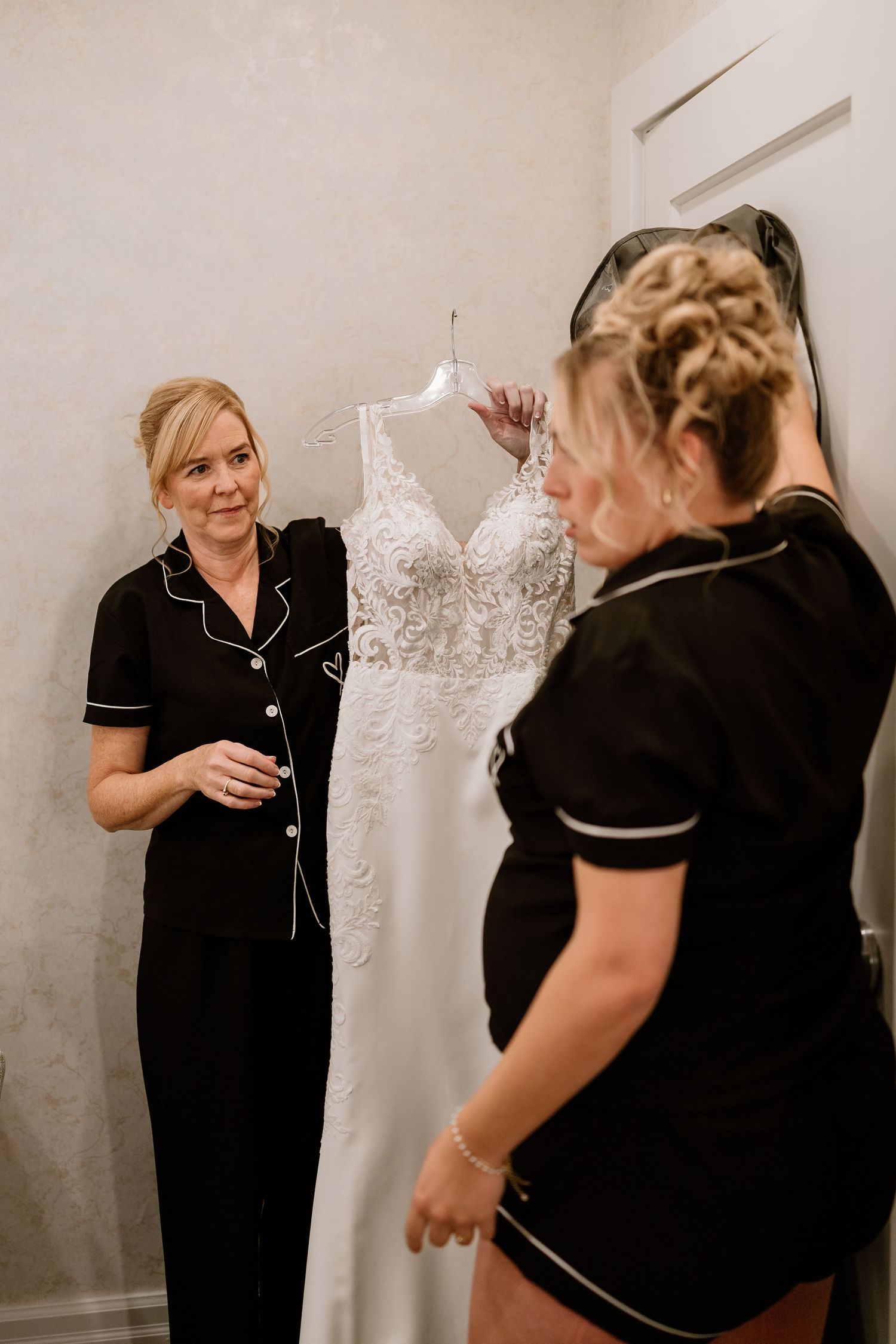 Wedding dress being prepared and displayed with attendants in black.