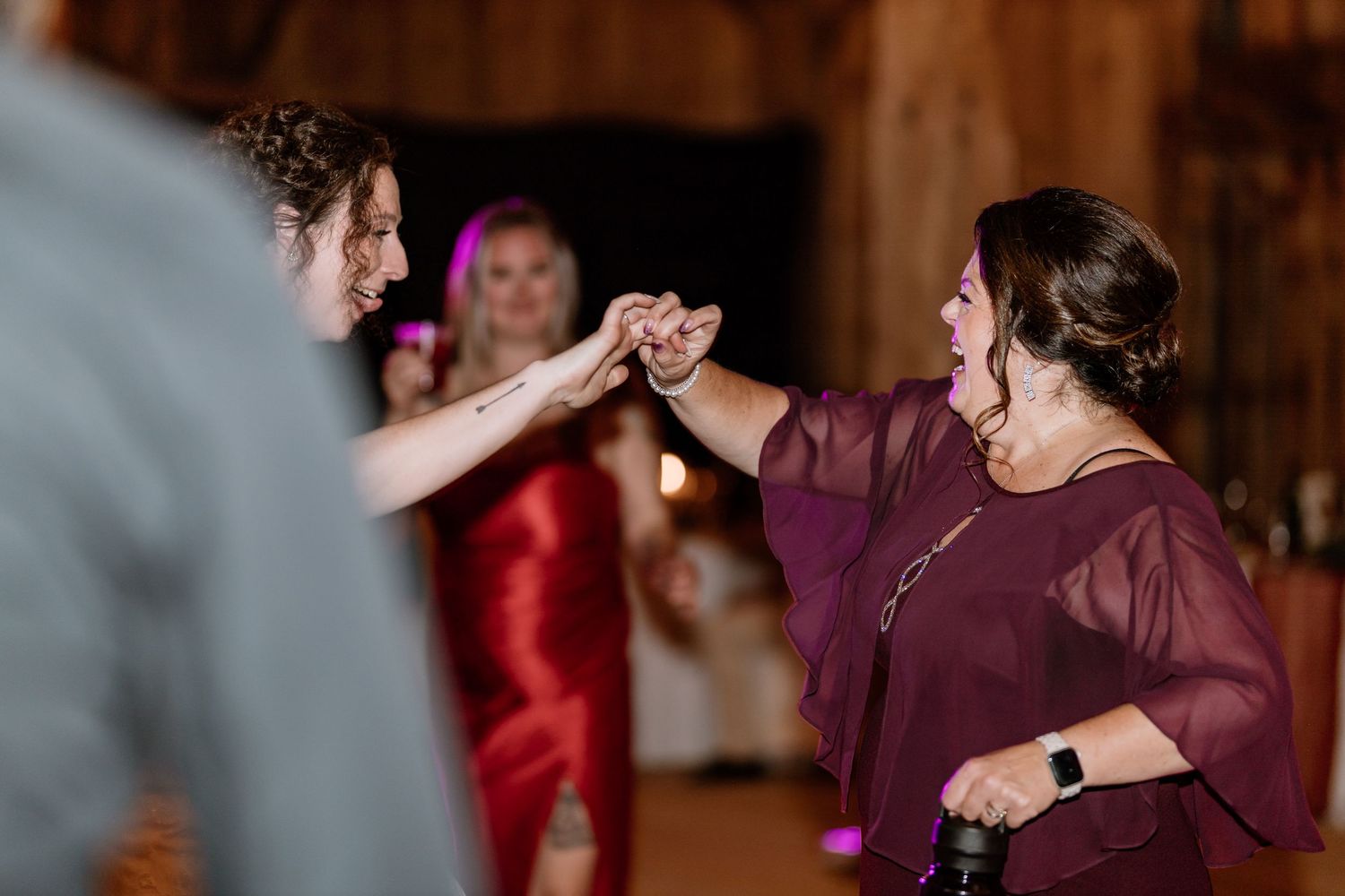 Wedding guests dancing and holding hands during reception celebration.