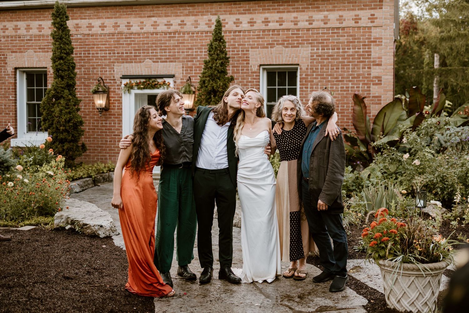 A celebratory group photo of wedding party members outside a brick building.