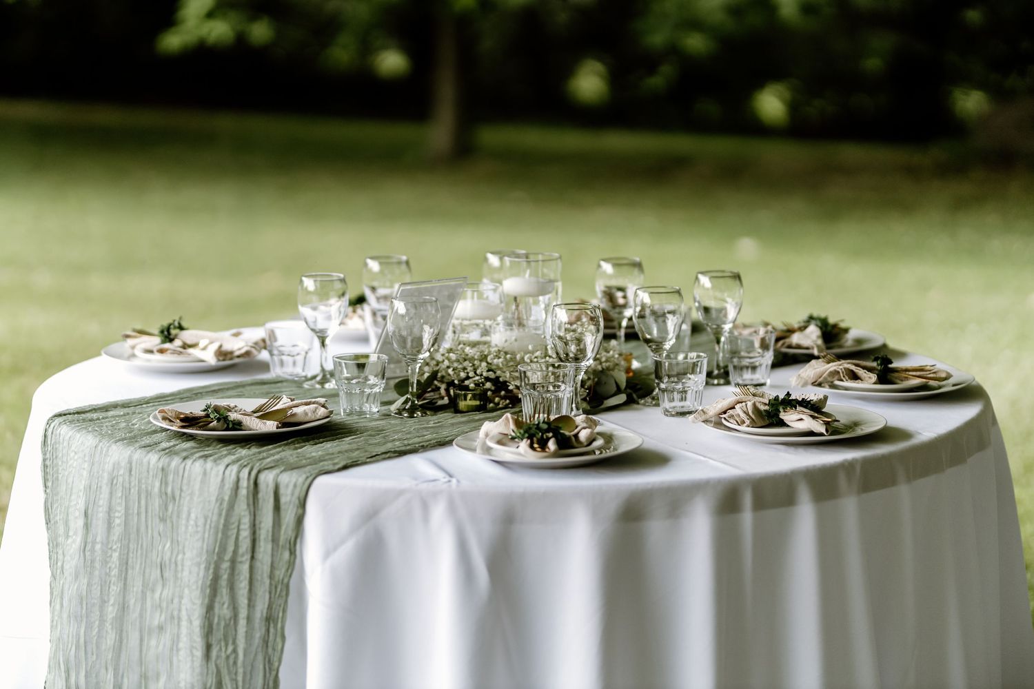 Elegant white table settings with floral centerpieces under a wedding tent.