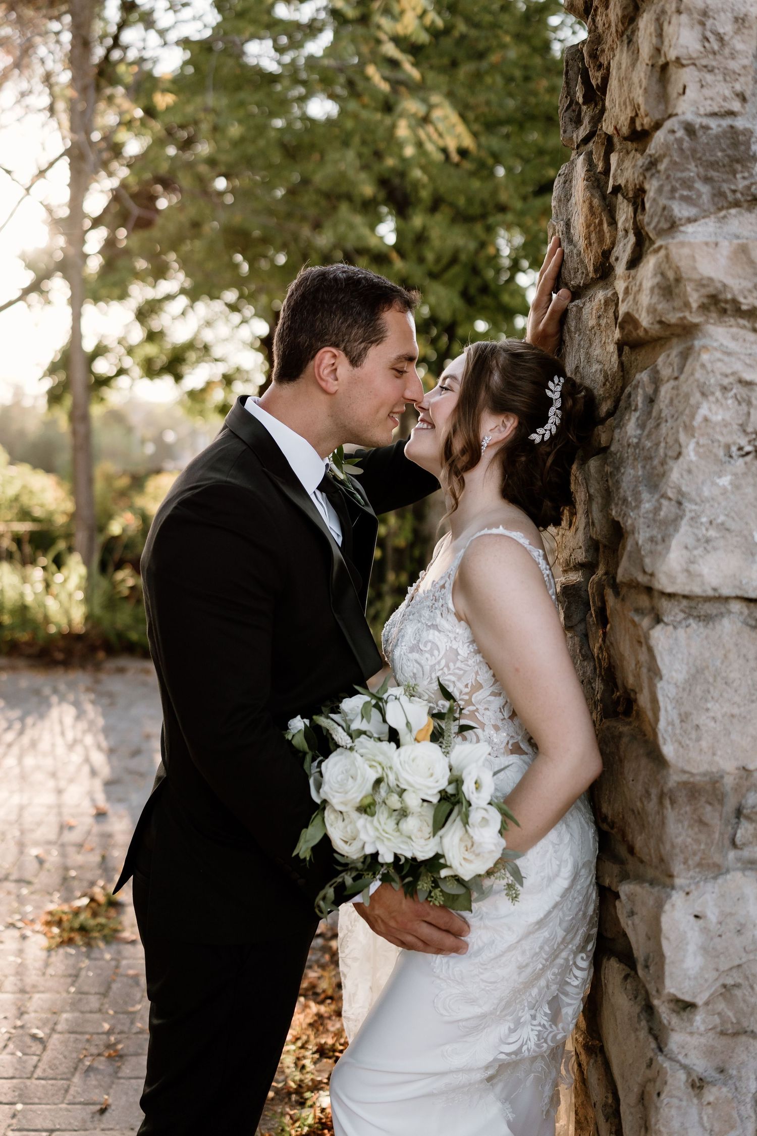 Romantic wedding portraits captured between stone pillars in natural lighting.