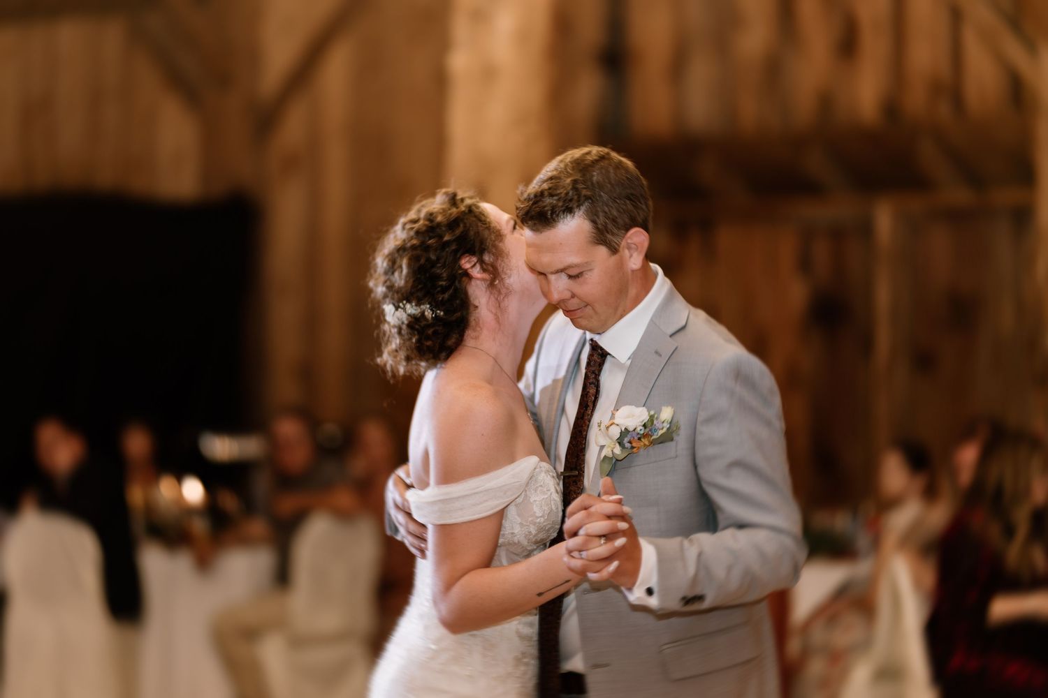 Romantic first dance in a rustic barn venue with string lights overhead.