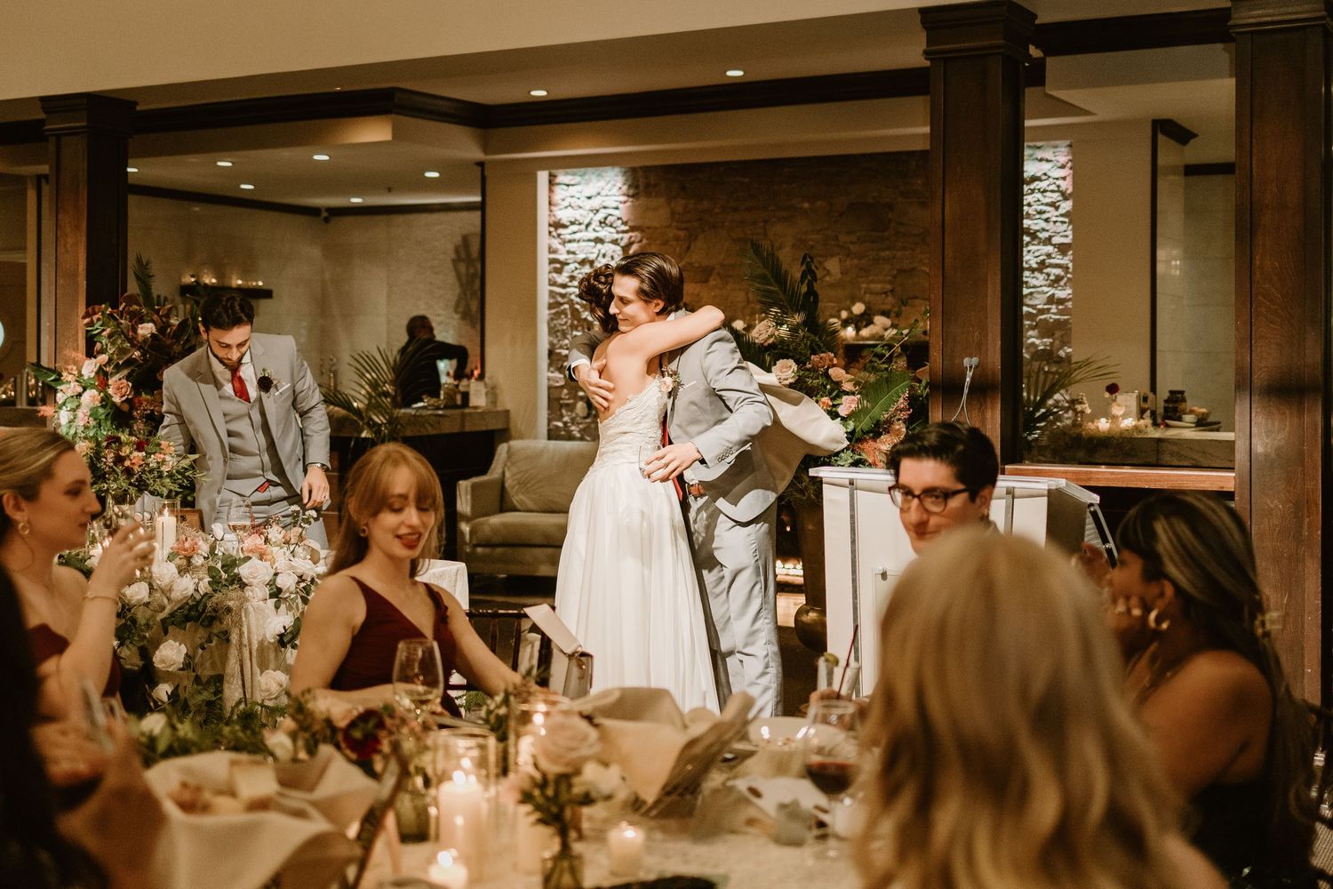 Wedding celebration in a banquet hall with guests seated at decorated tables under ambient lighting.