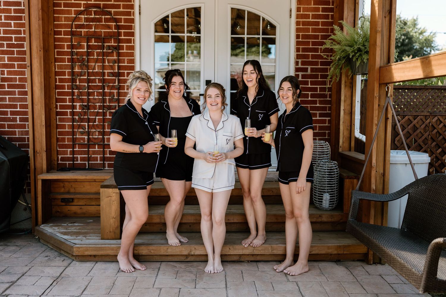 Group wearing matching black and white loungewear sitting on brick porch.