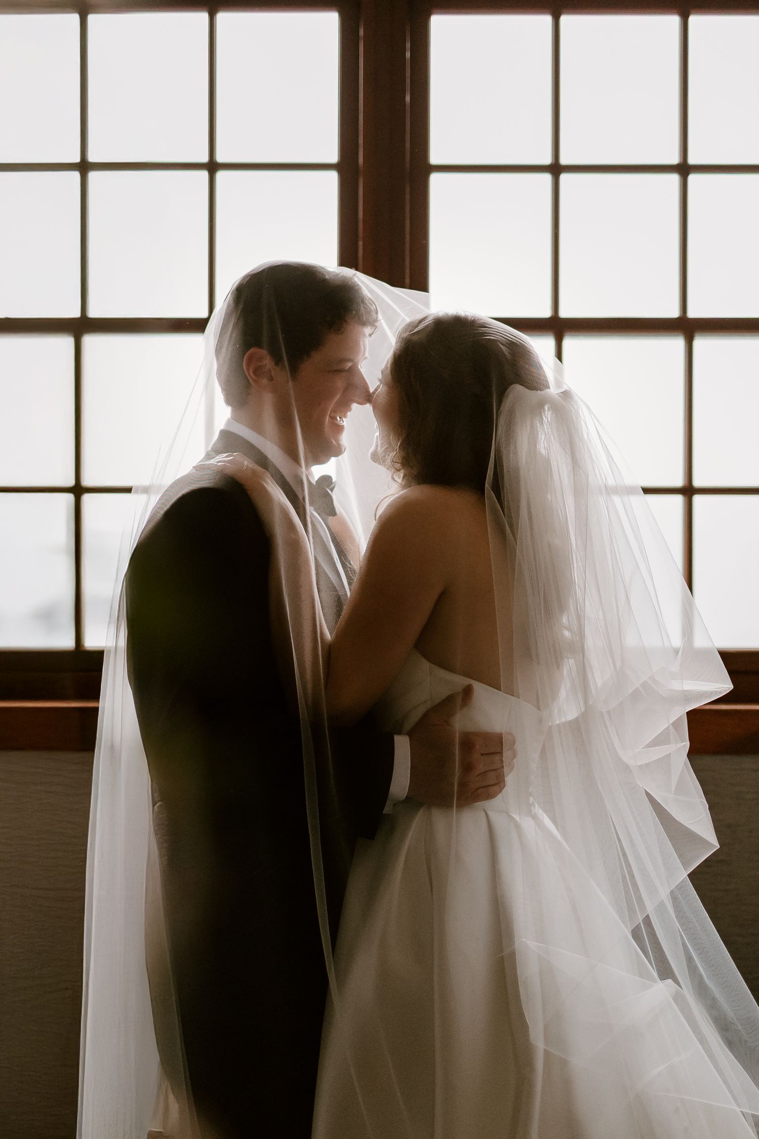 Artistic silhouette of a wedding couple against bright window light.