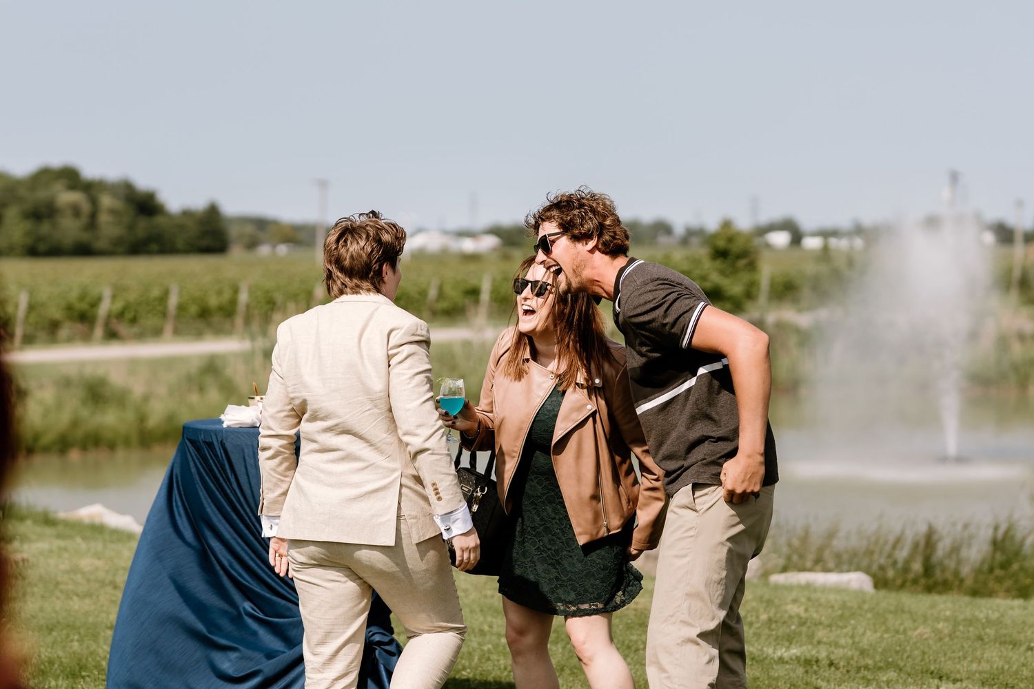 Wedding guests chatting and socializing near a fountain in an outdoor venue.