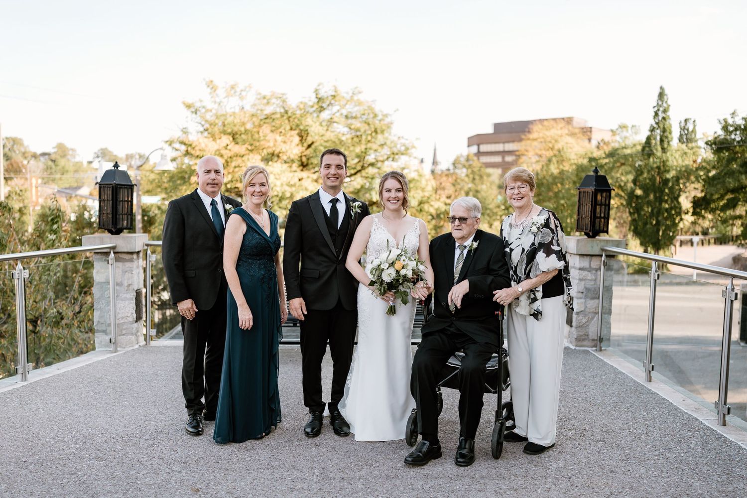Formal group portrait of wedding party on modern outdoor balcony.