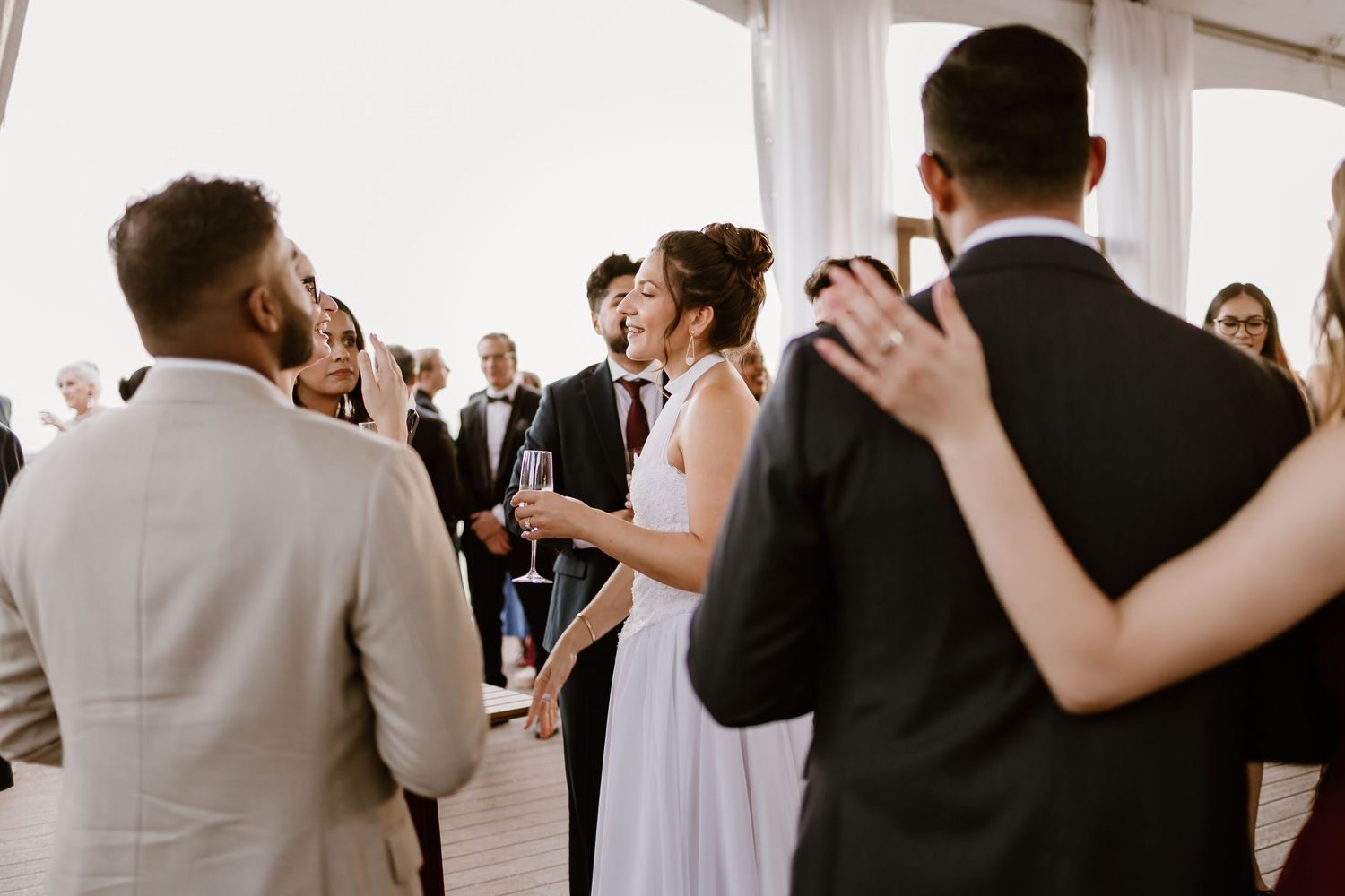 Wedding guests dance and socialize during a lively indoor reception celebration.