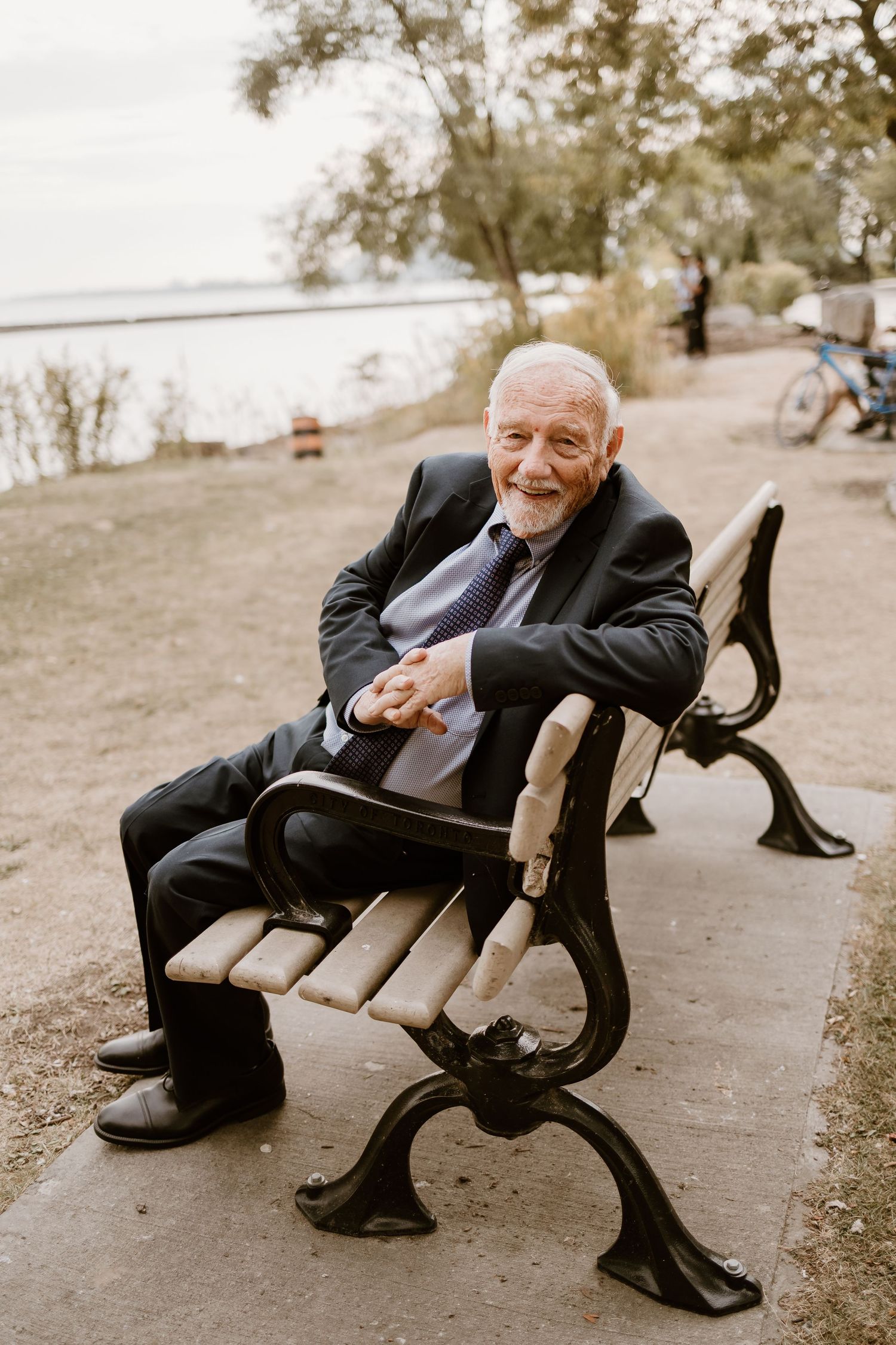 Person in formal attire lounging on park bench in casual pose.