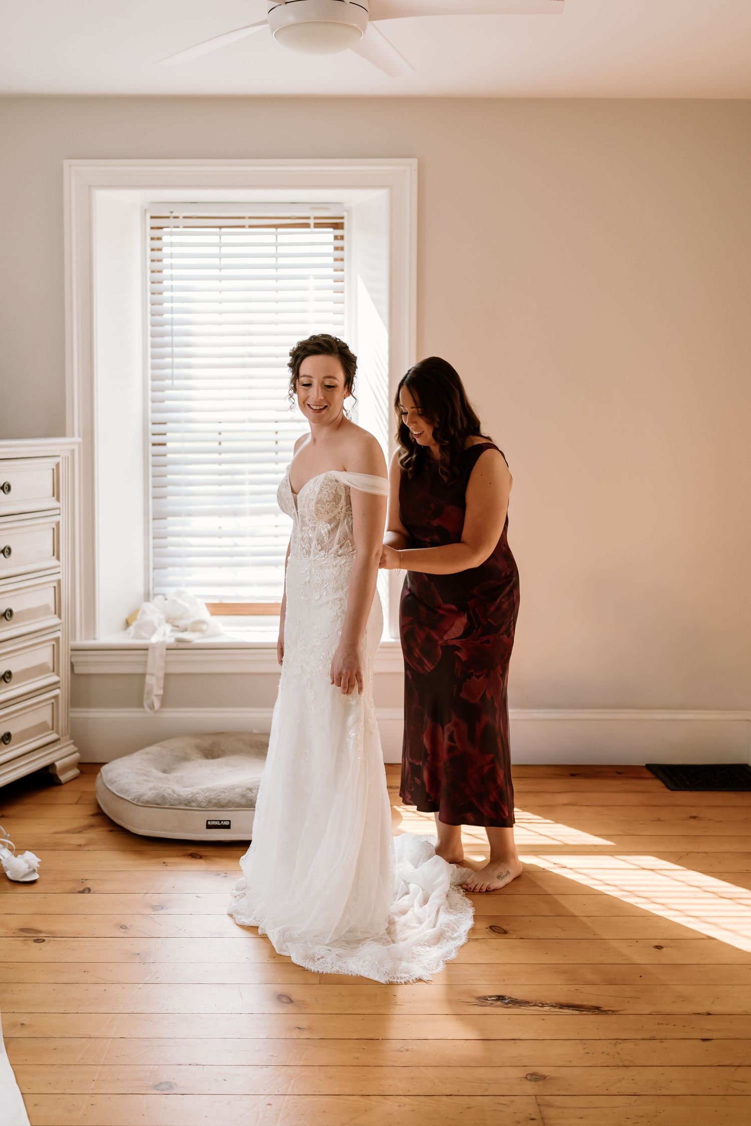 Sunlight streams through windows during wedding dress fitting in a bright room.