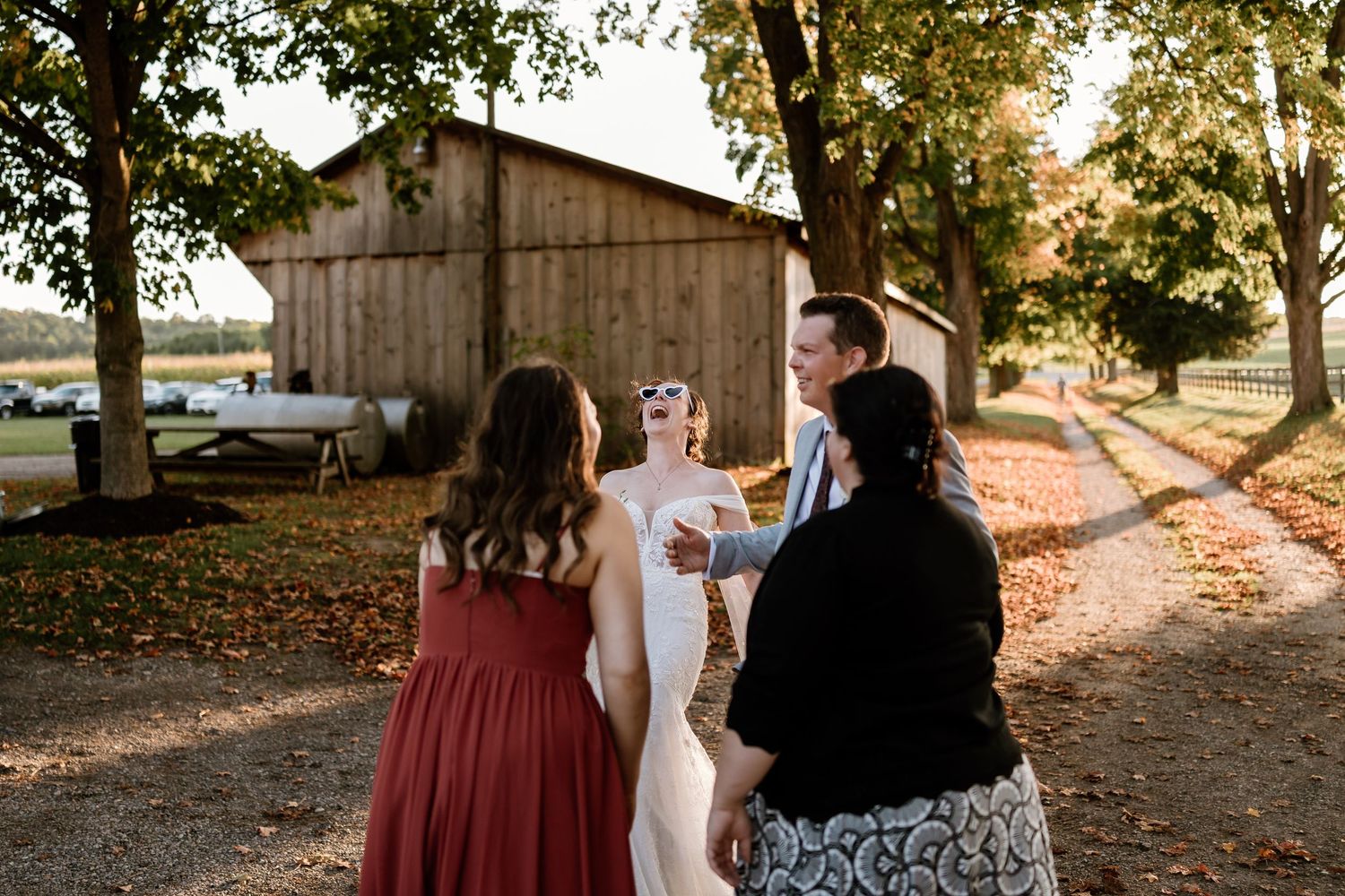 Wedding party walks along a tree-lined path during sunset.