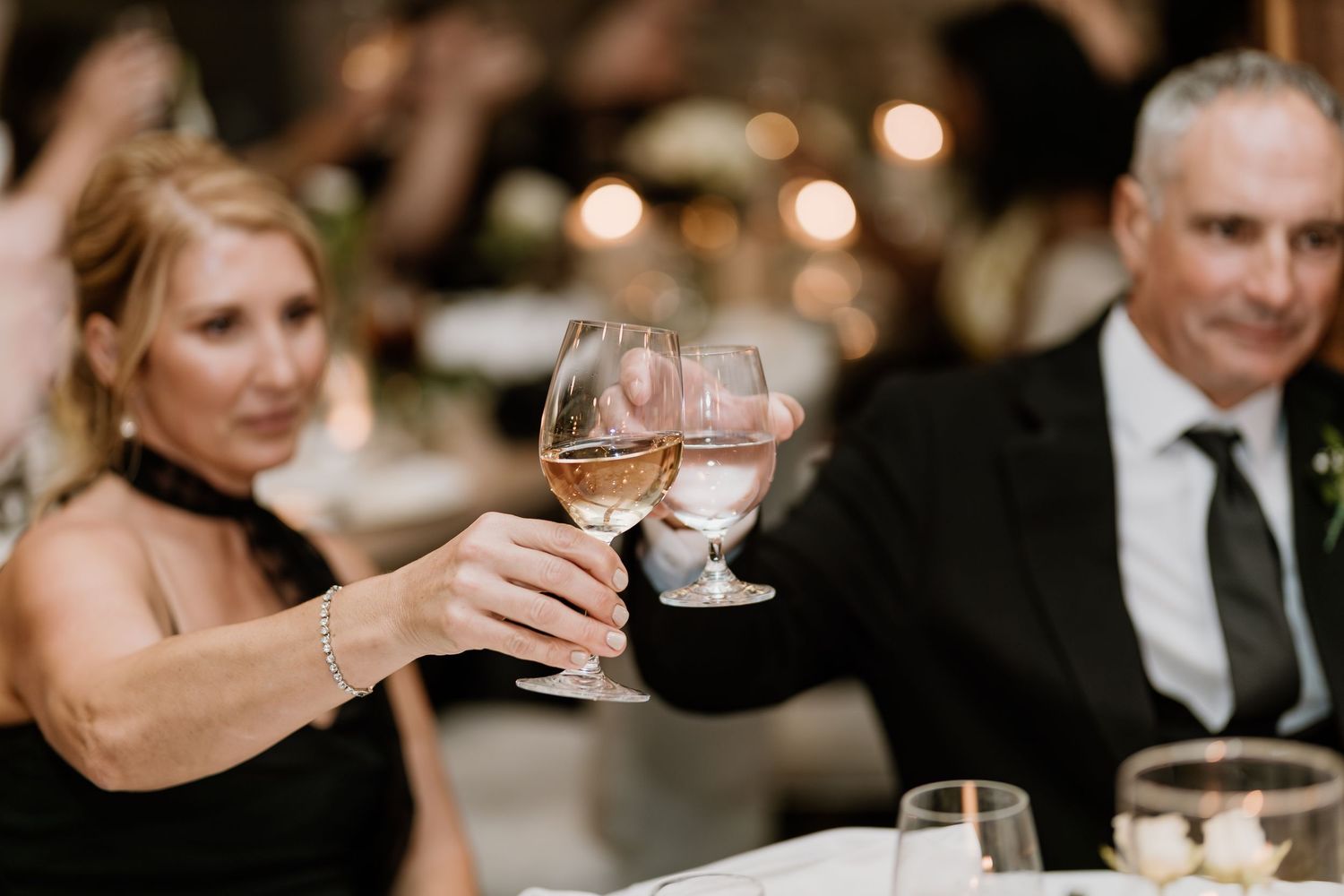 Formal dinner guests share laughter and conversation at an elegant wedding reception.