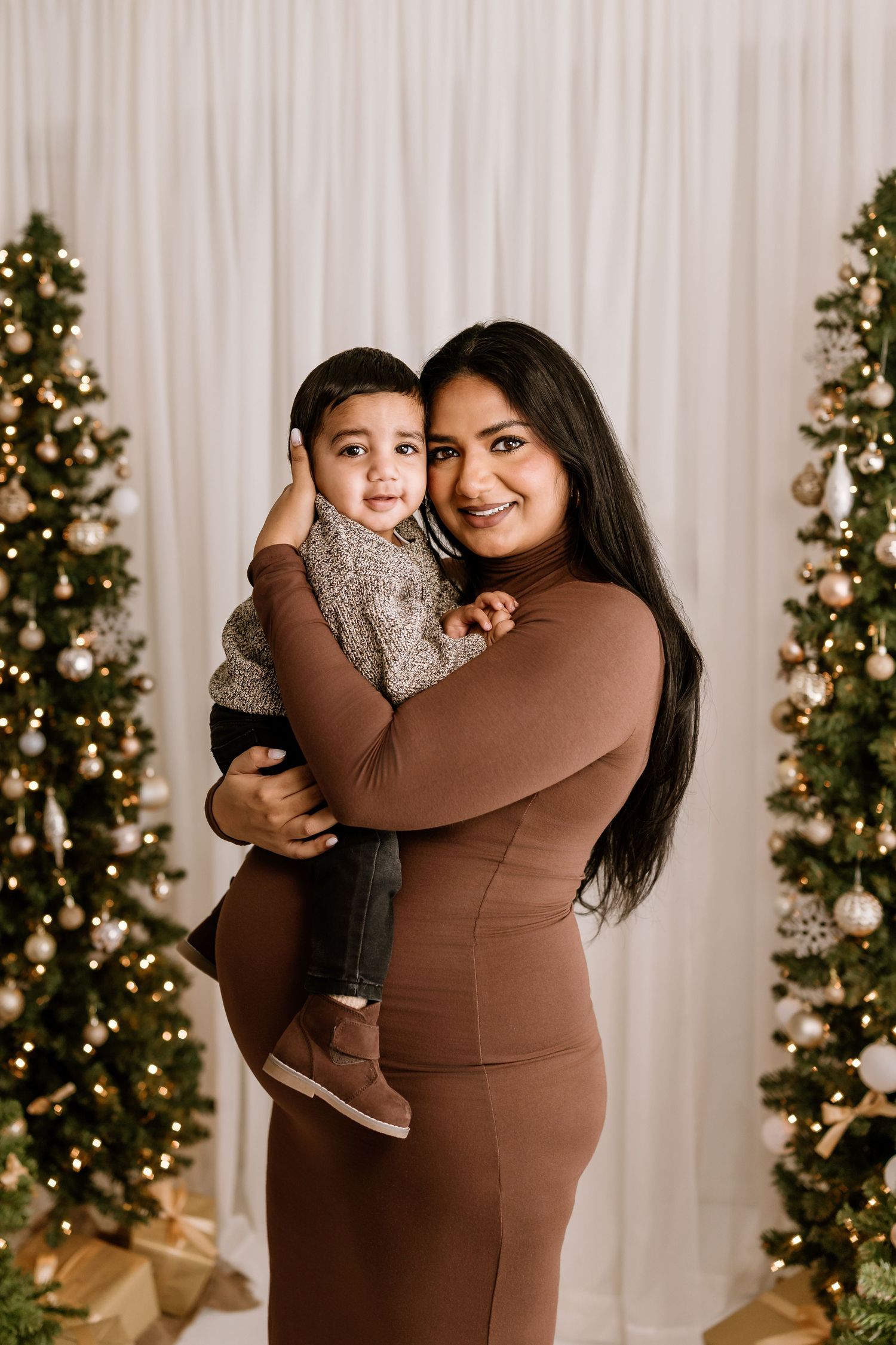 Tender family moment in front of decorated Christmas trees and wrapped presents.