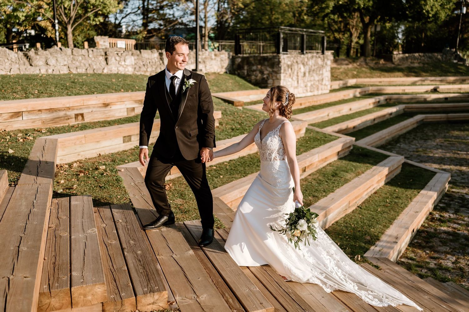 Couple walks along wooden deck stairs during golden hour wedding photoshoot.