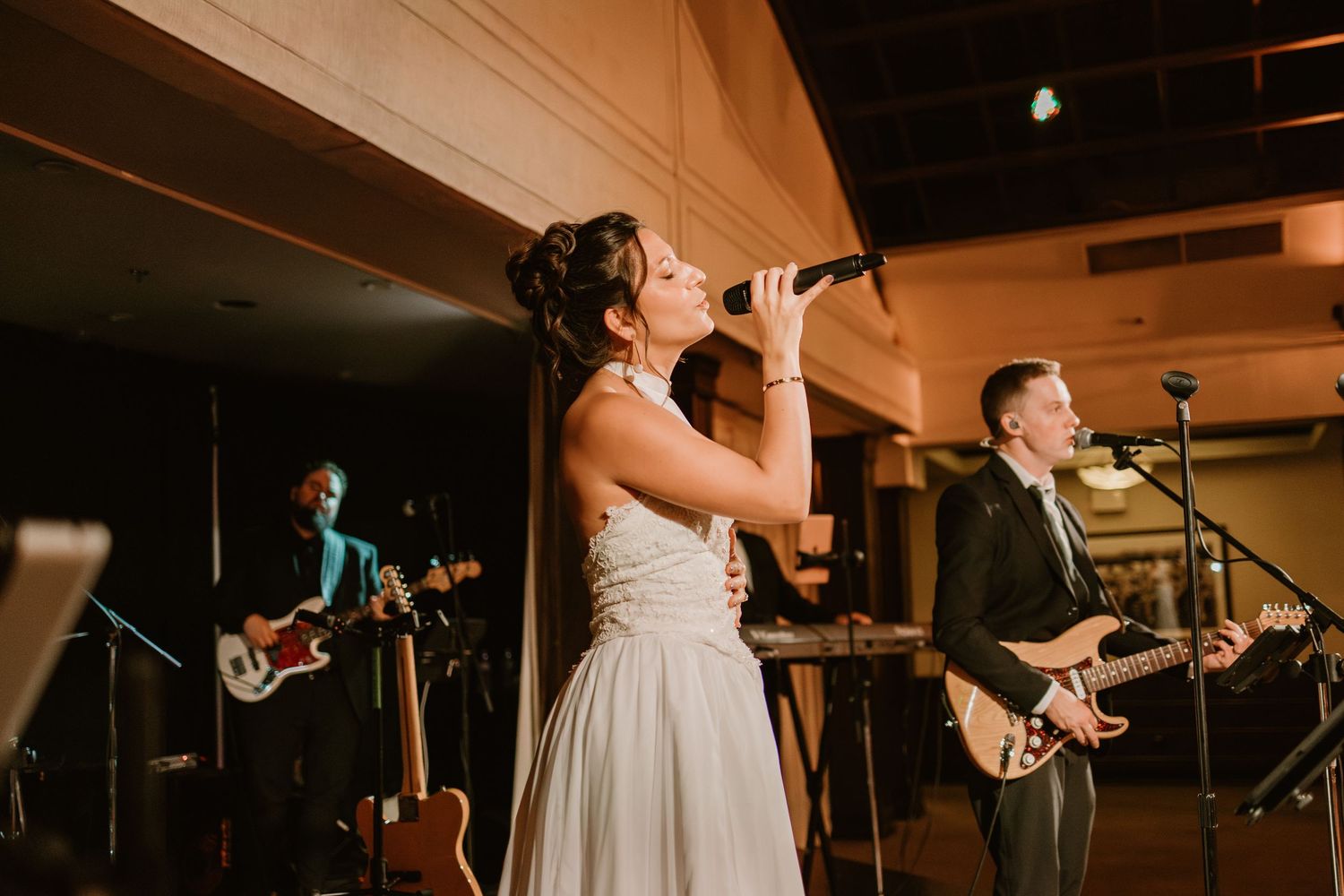 Musicians playing instruments on stage during an evening wedding celebration.