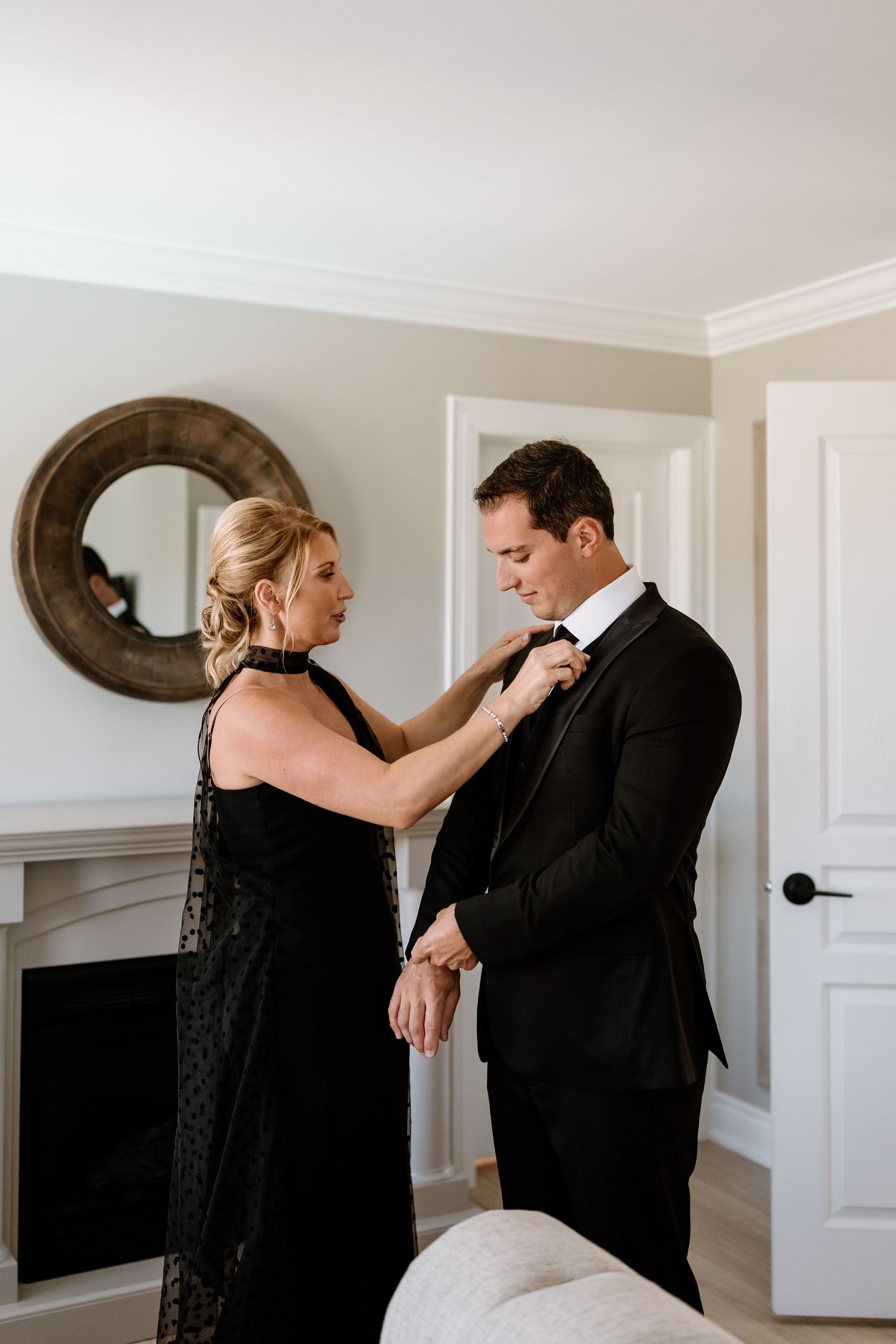Formal dressing scene with black evening gown and suit in bright interior setting.