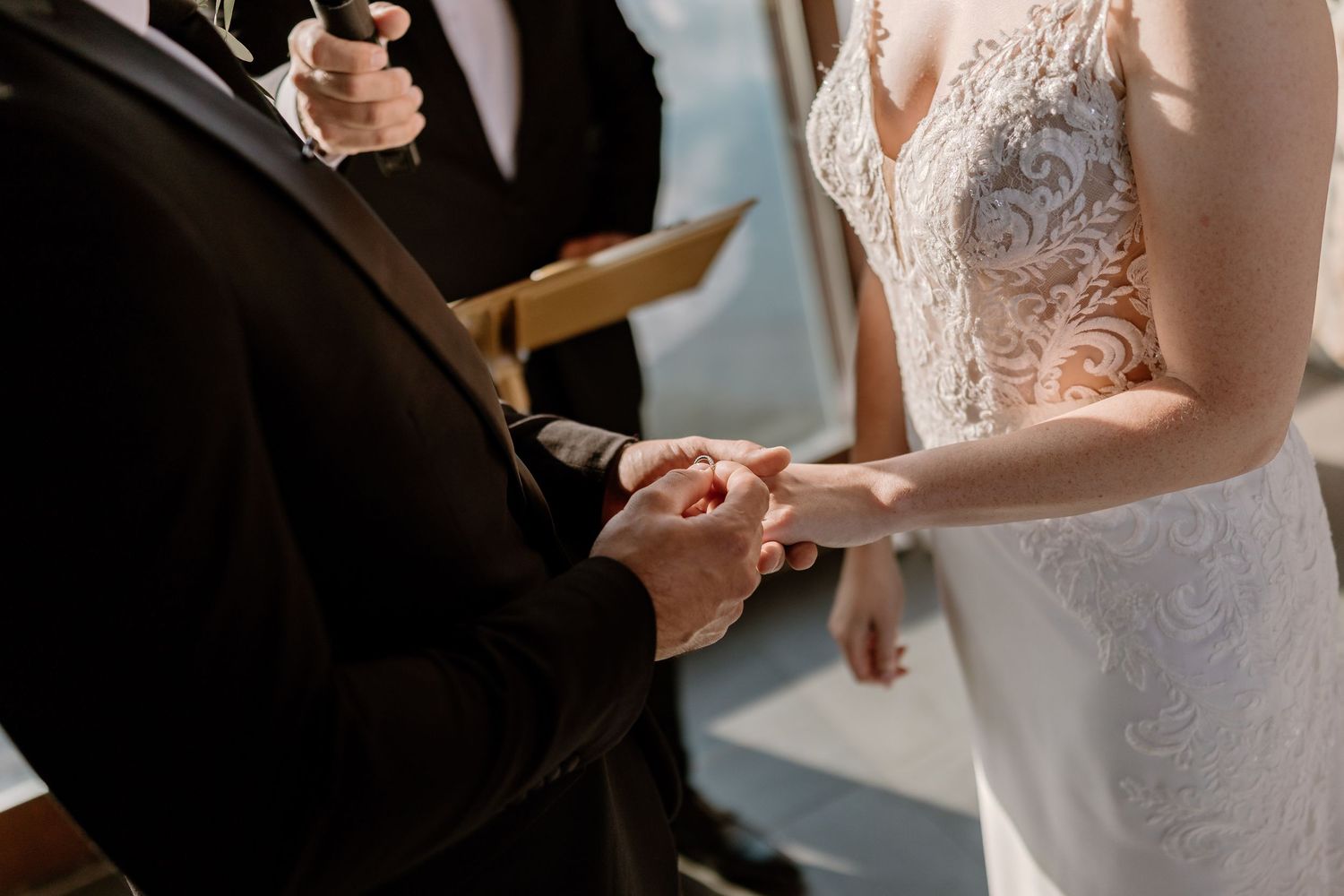 Close-up of couple's hands during wedding ceremony vow exchange.