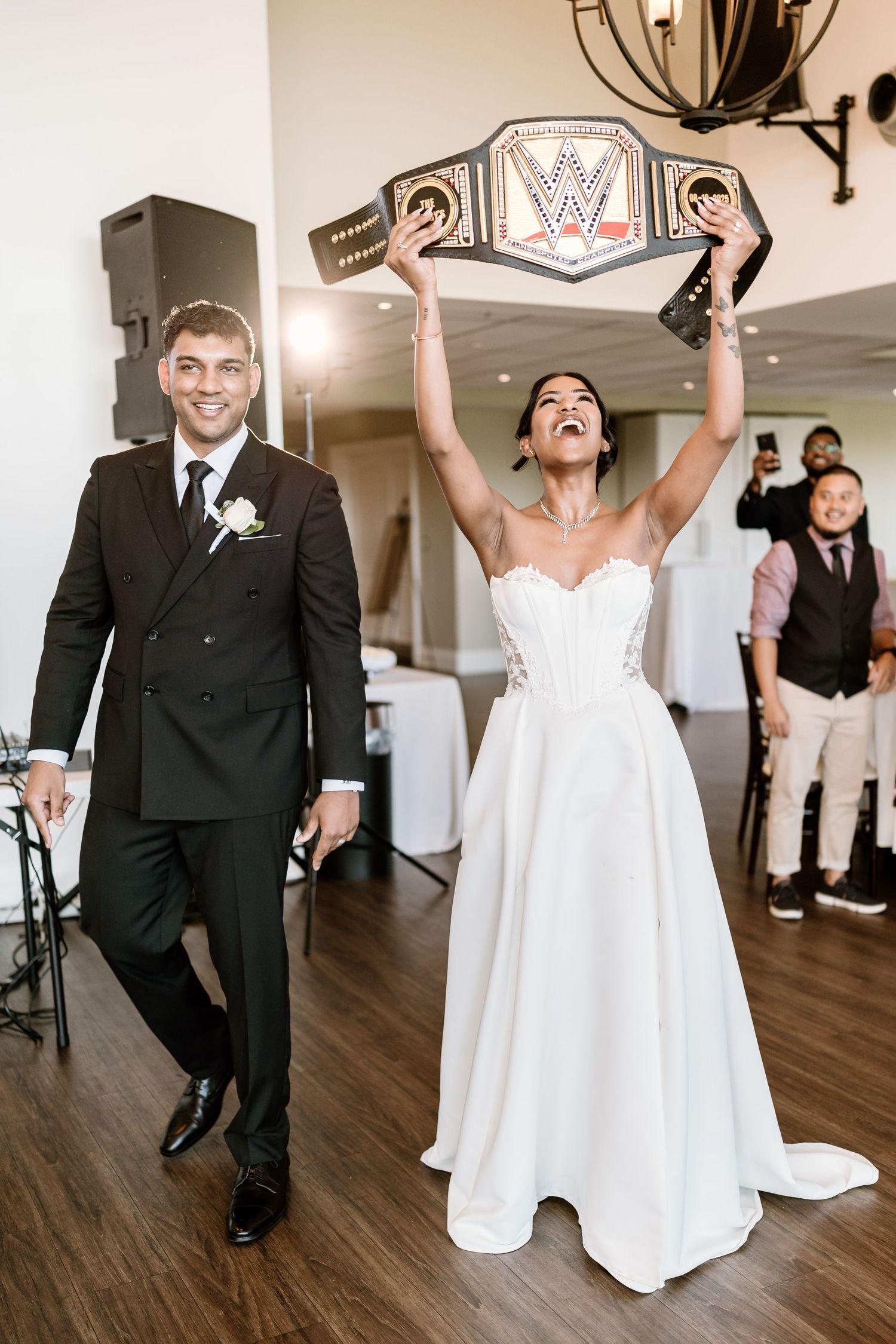 Newlyweds celebrate with joyful dance moves on a wooden floor at their wedding reception.