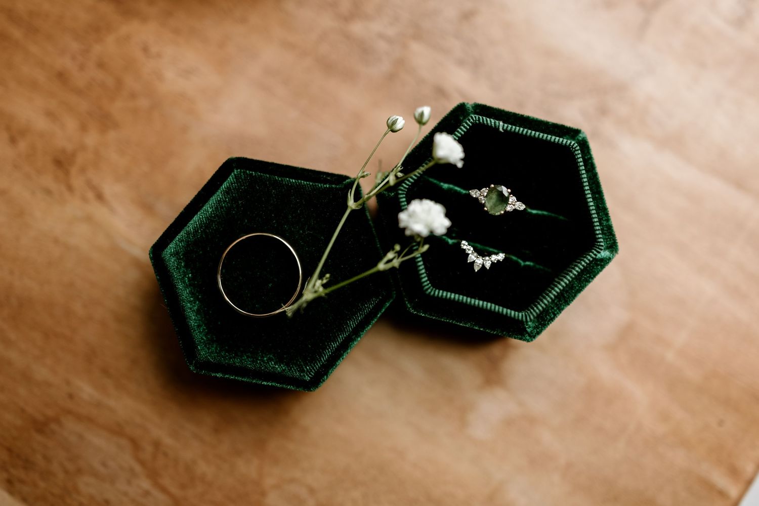 Dark velvet ring boxes displayed on beige surface showcasing wedding jewelry.