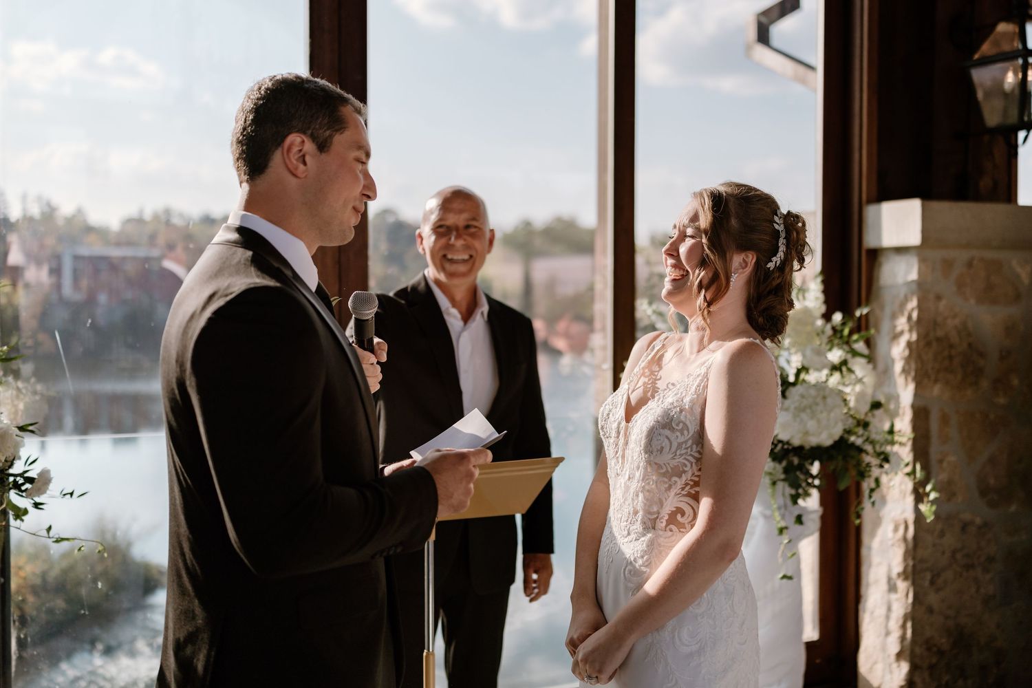 Wedding ceremony candid moments captured in a venue with panoramic windows.