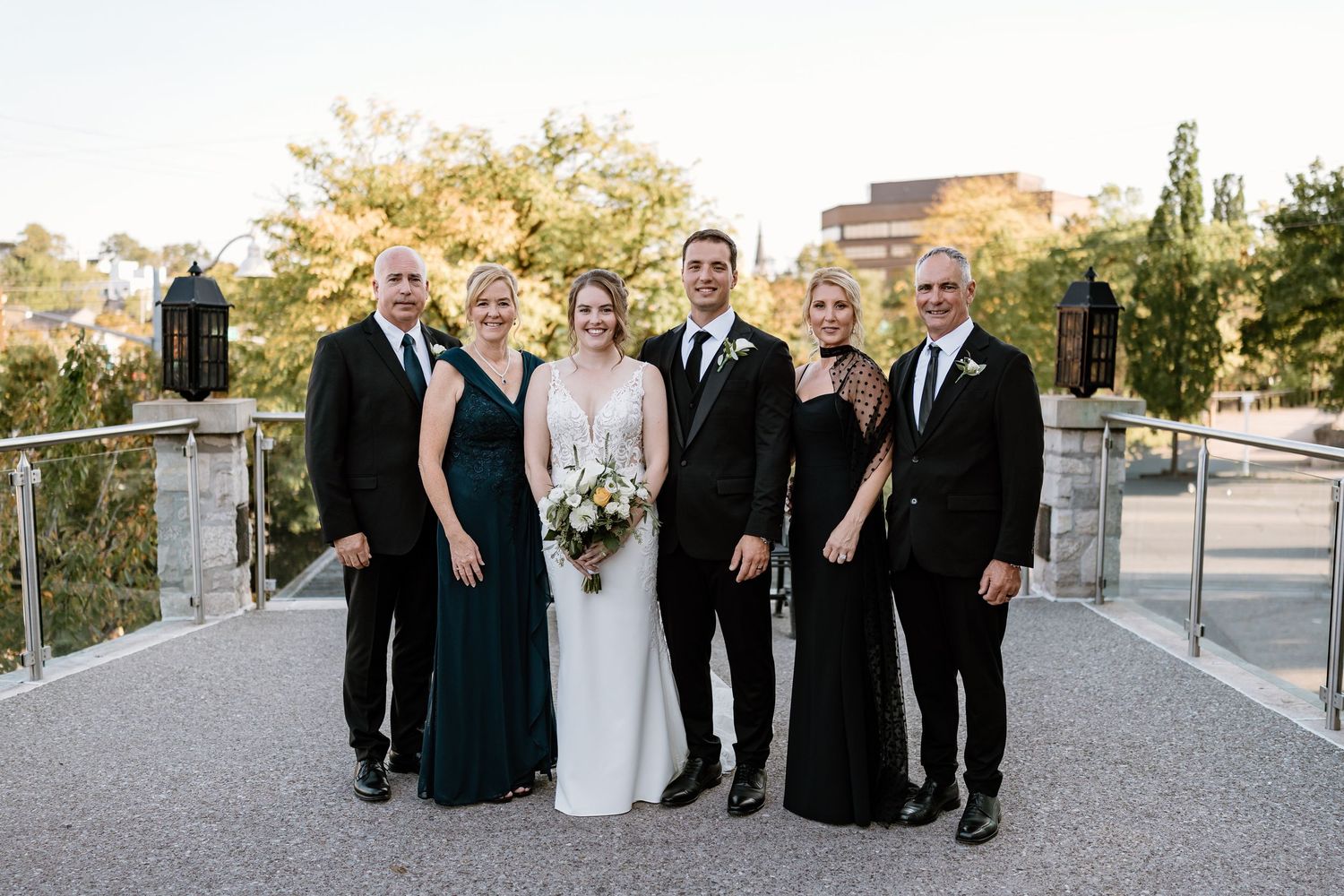 Wedding party poses together on outdoor terrace with formal attire.