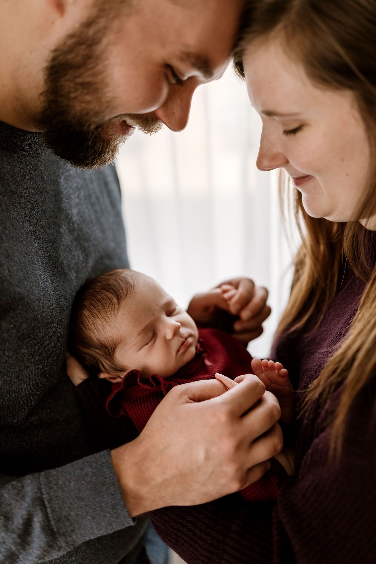 Intimate black and white portrait of parents sharing a tender moment with their newborn.