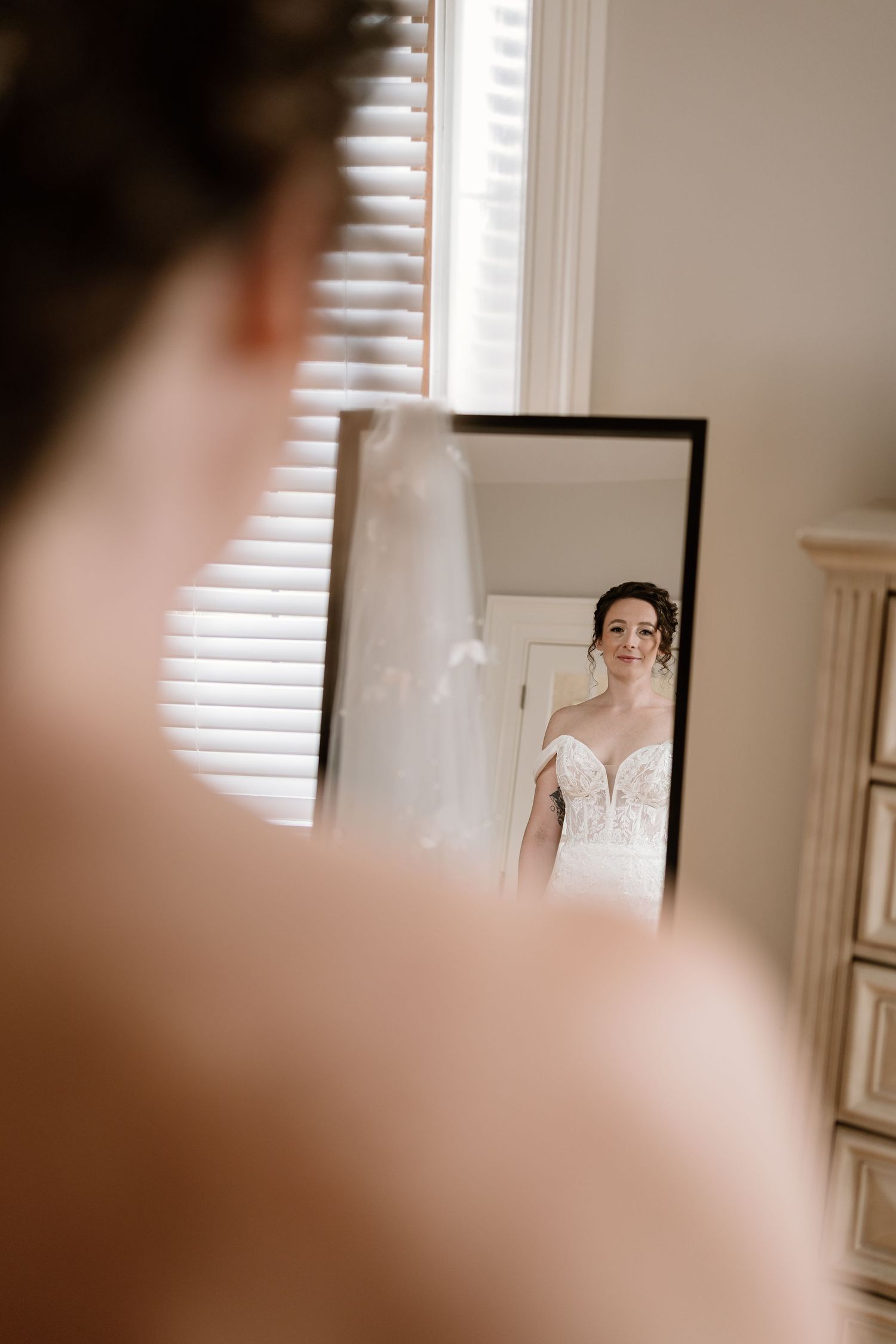 A mirror reflection shows someone getting ready in a sunlit room.