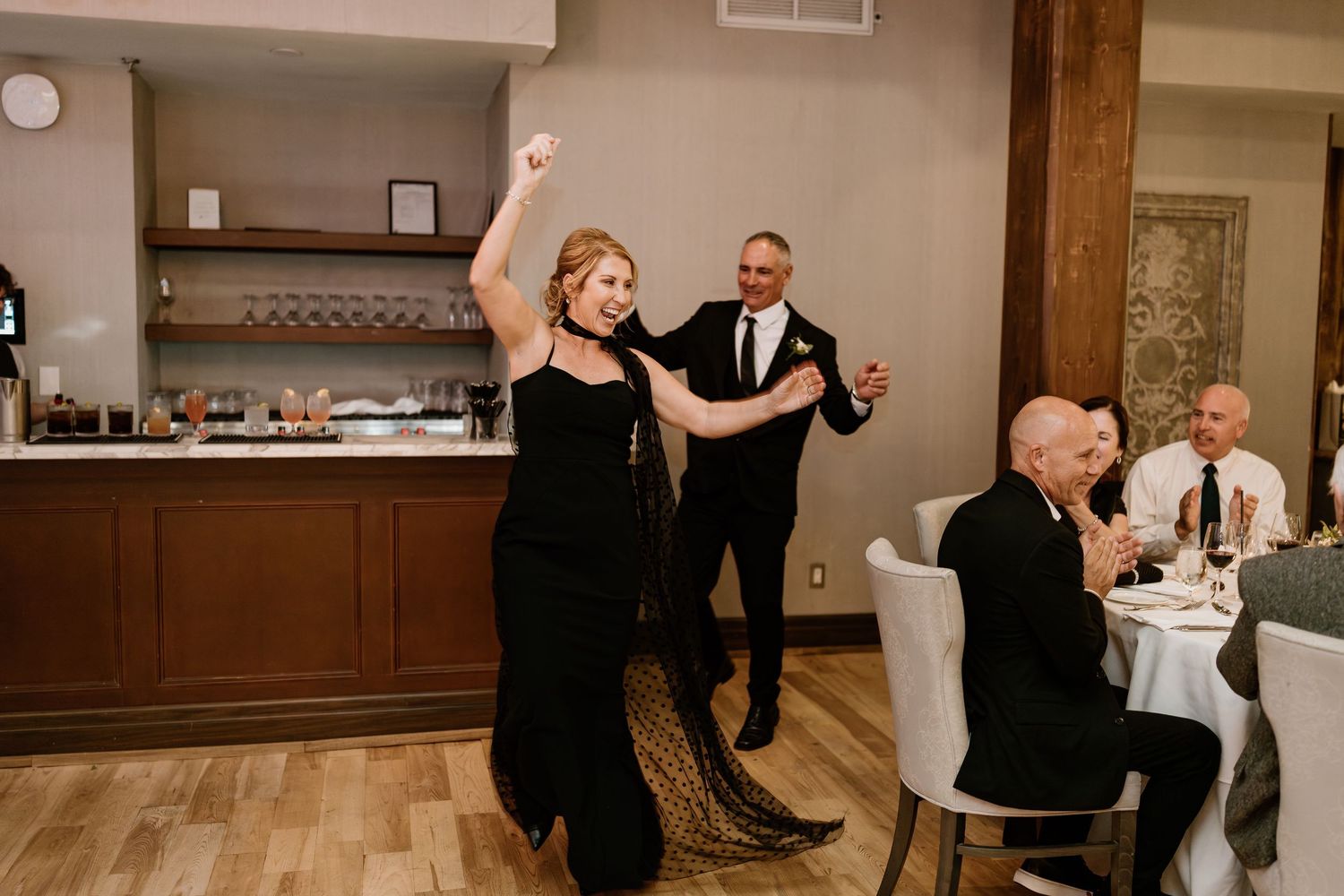 Energetic dancers in black attire performing at an elegant wedding reception.