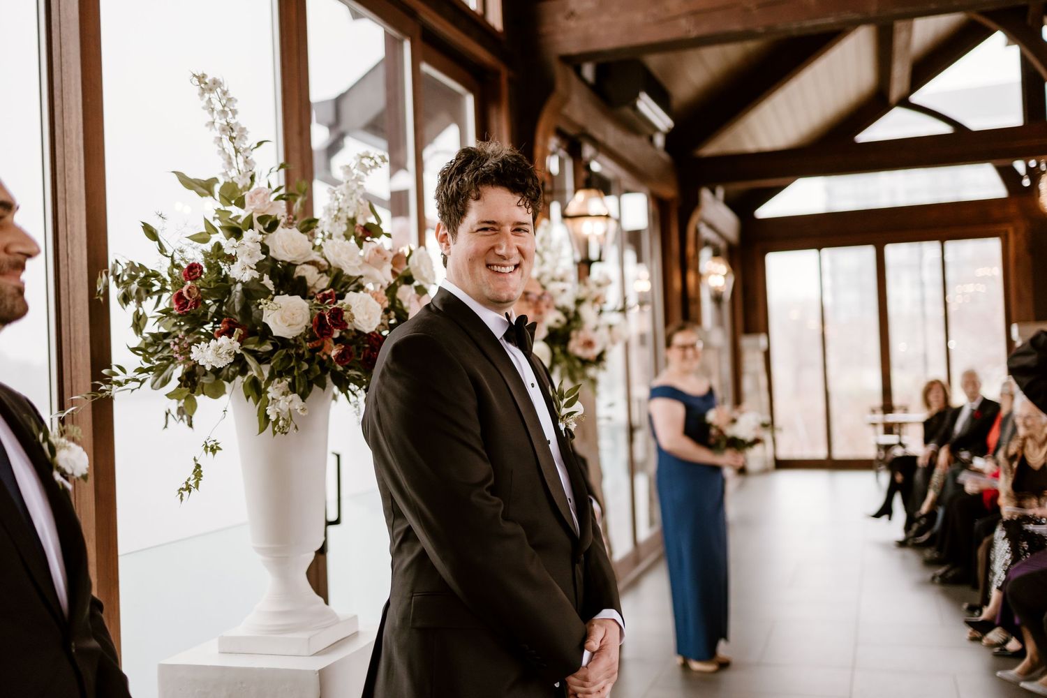Wedding ceremony venue decorated with floral arrangements and wooden beams overhead.