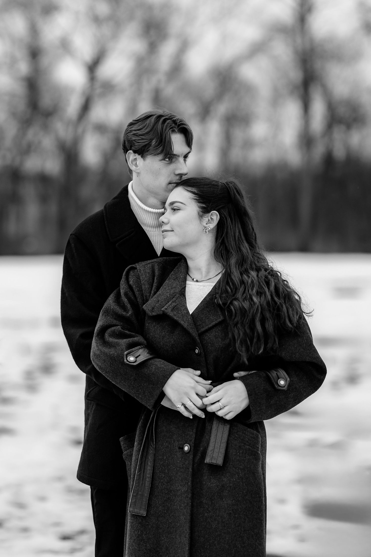 A black and white portrait of a couple embracing in winter attire.