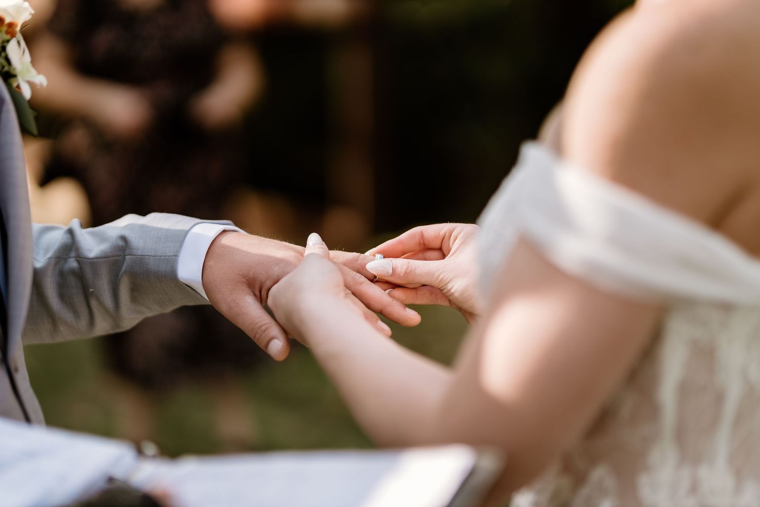 Close-up of ring exchange during outdoor wedding ceremony.