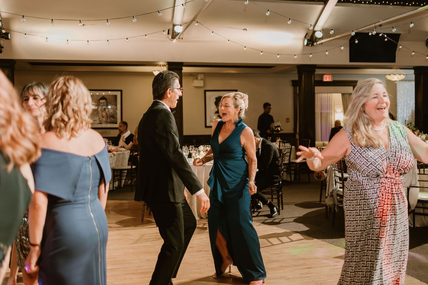 Wedding guests mingling and dancing in an elegantly decorated reception hall.