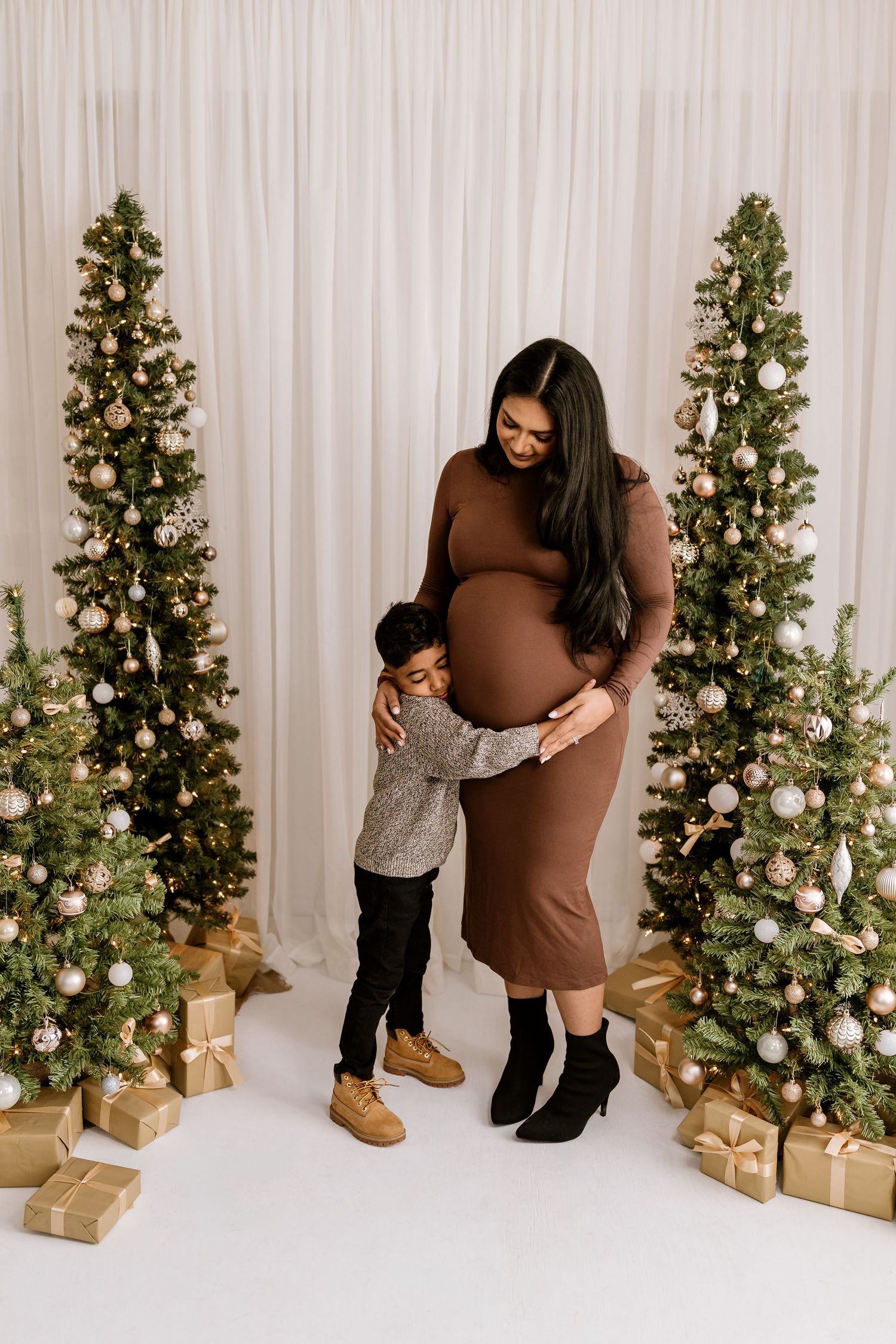 Heartwarming family interaction captured against white curtains and lit Christmas trees.