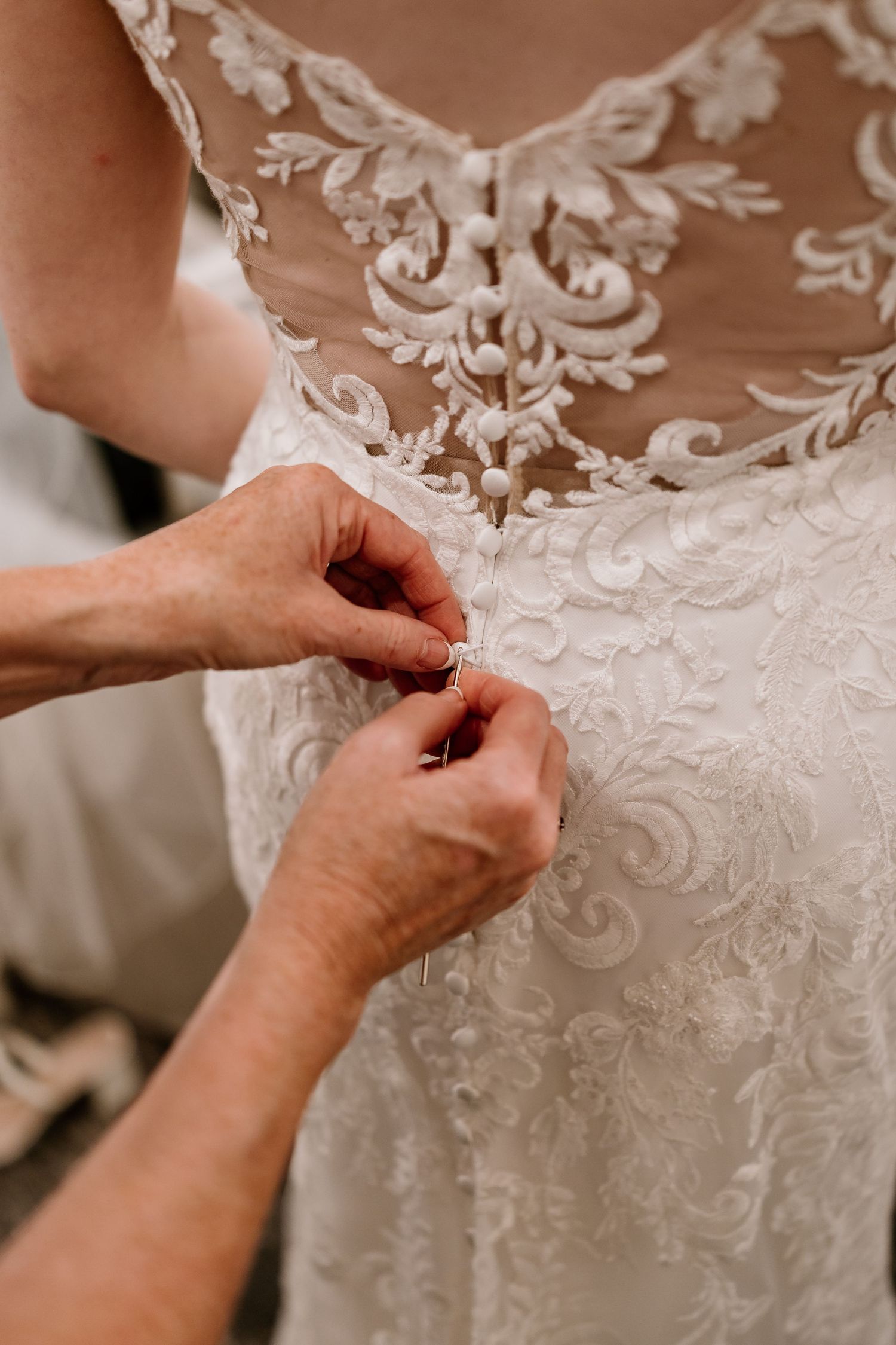Detailed view of intricate lace patterns on a white wedding dress during alterations.
