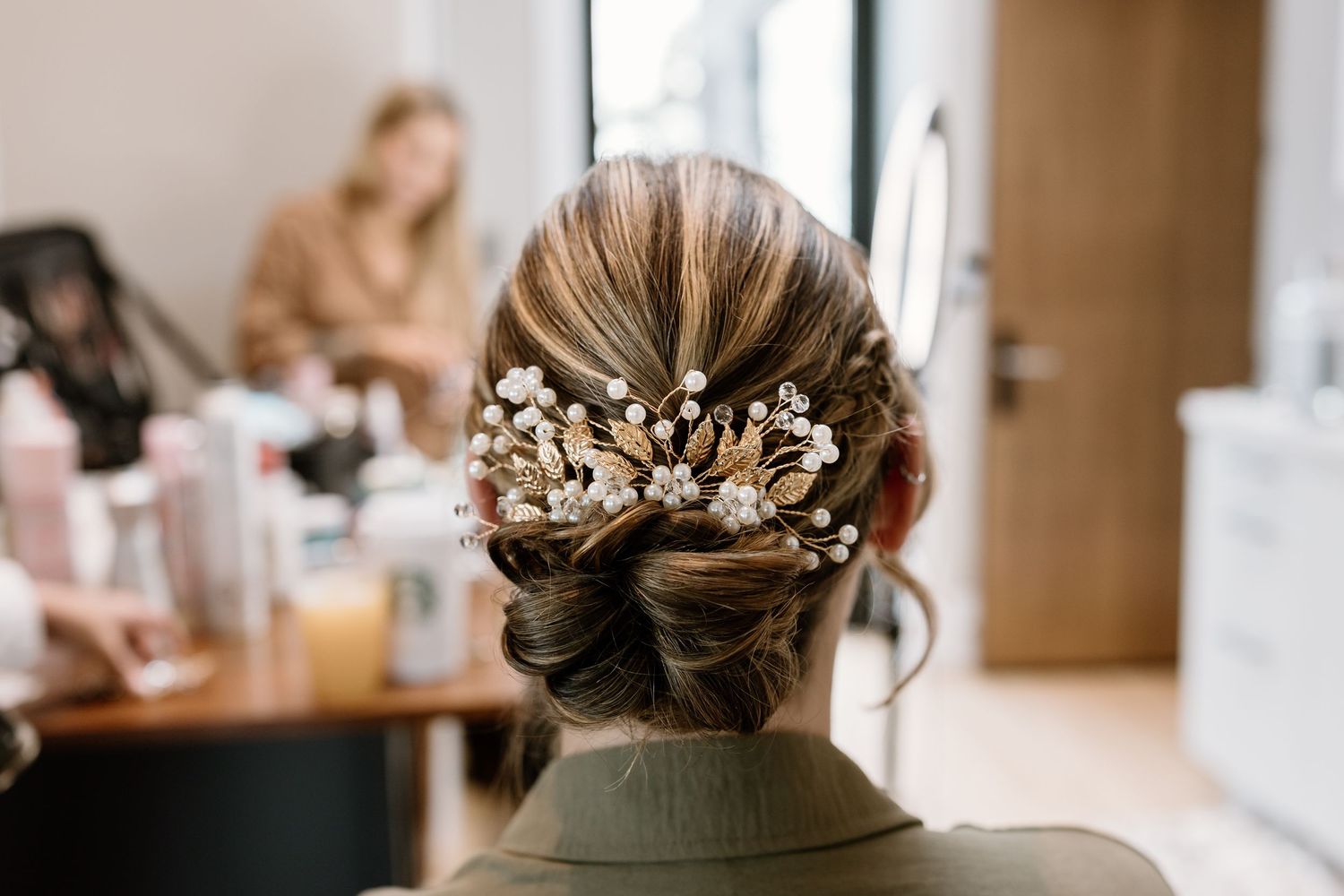 Wedding day hair and makeup preparation scene in natural lighting.