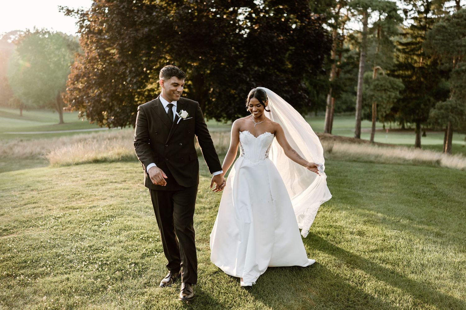 Couple dances together on rolling green hills during outdoor wedding photoshoot.