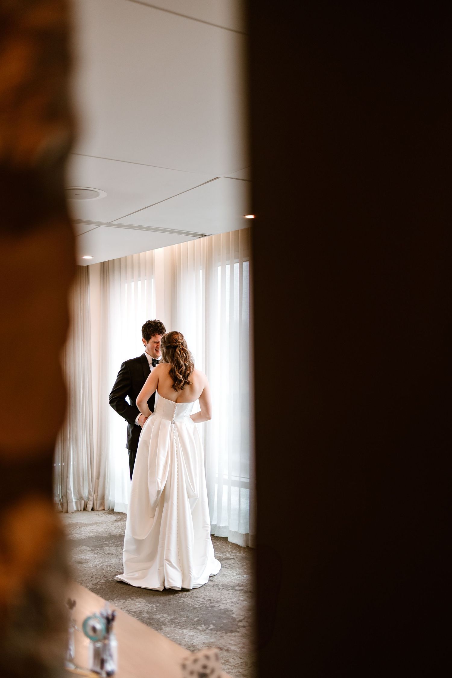 Wedding couple shares a private moment in an elegant room with natural lighting.