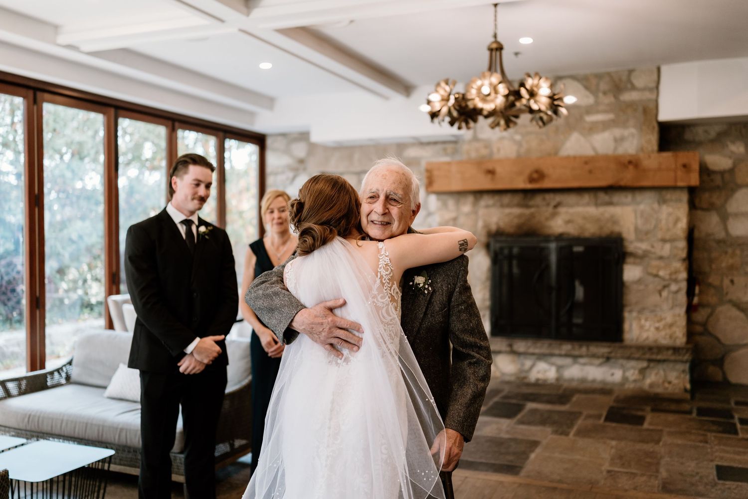 Elegant indoor wedding ceremony in a rustic stone venue with chandelier lighting.