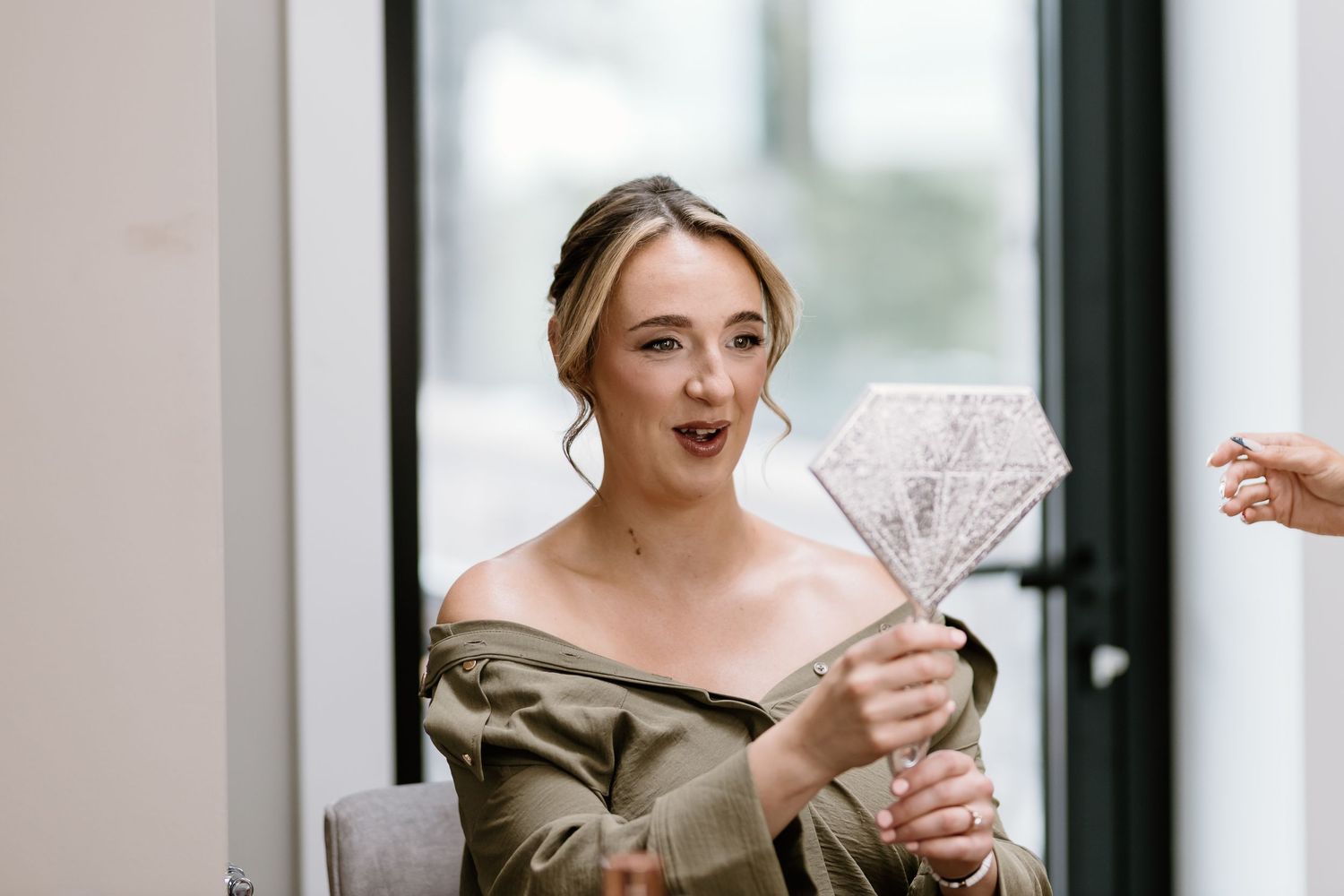 Wedding guest holds up a diamond-shaped decorative prop with a playful expression.