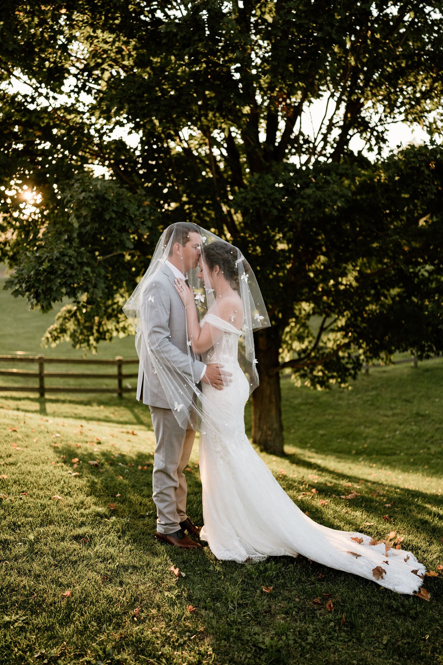 Romantic wedding couple embracing on a grassy hillside during golden hour.