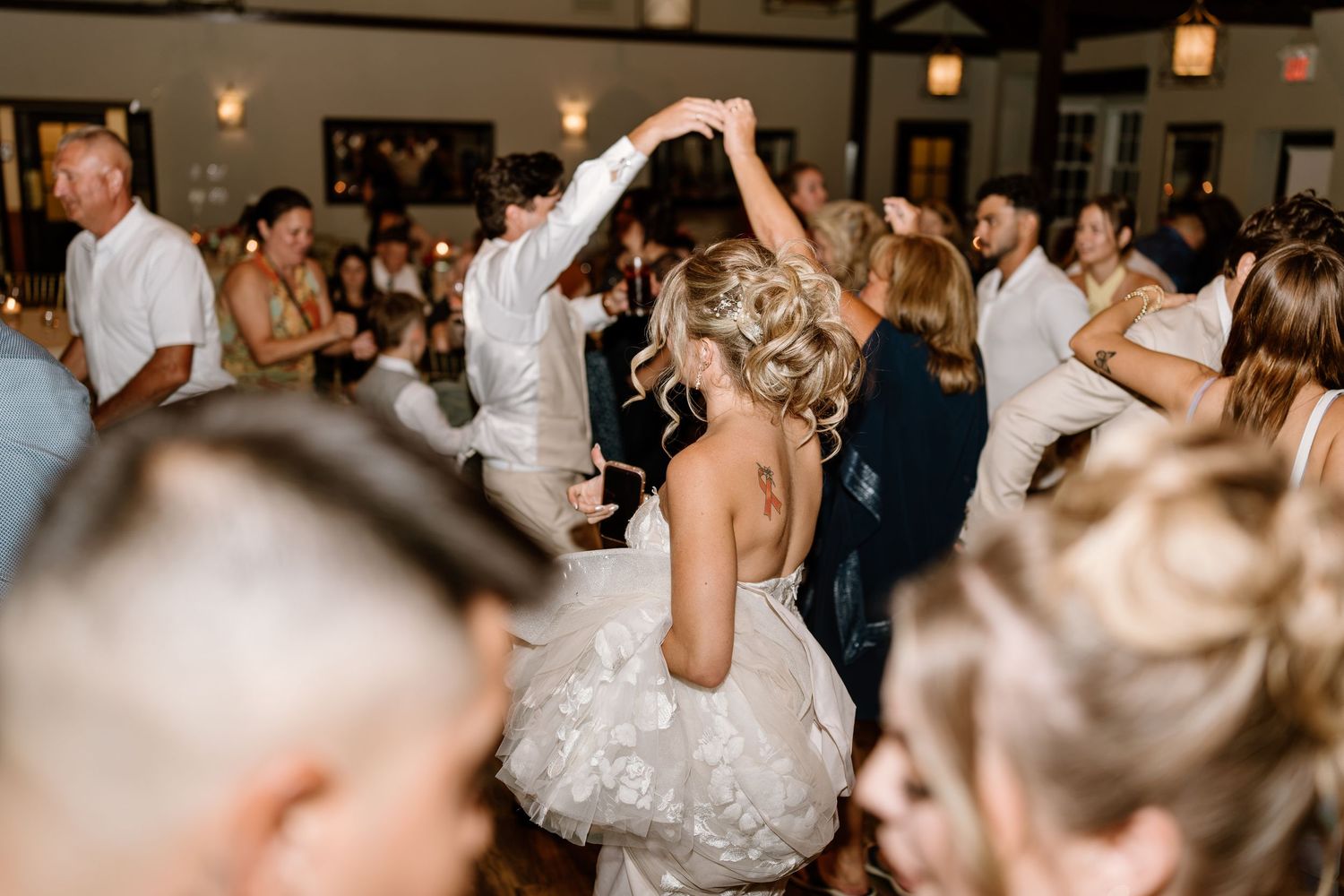 Bride in white ruffled dress dancing with groom at elegant indoor wedding reception celebration.