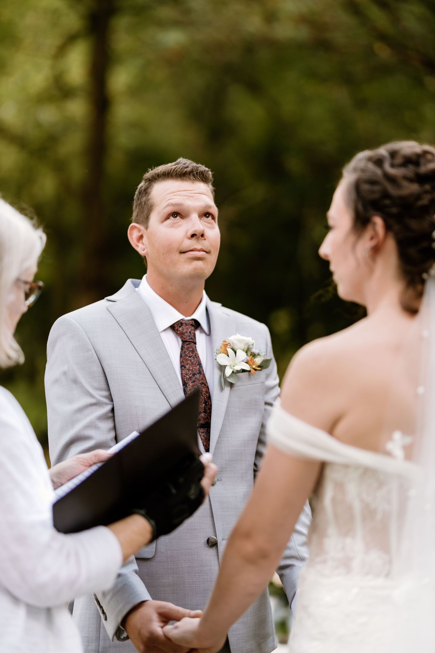Emotional exchange during wedding ceremony with officiant holding black book.