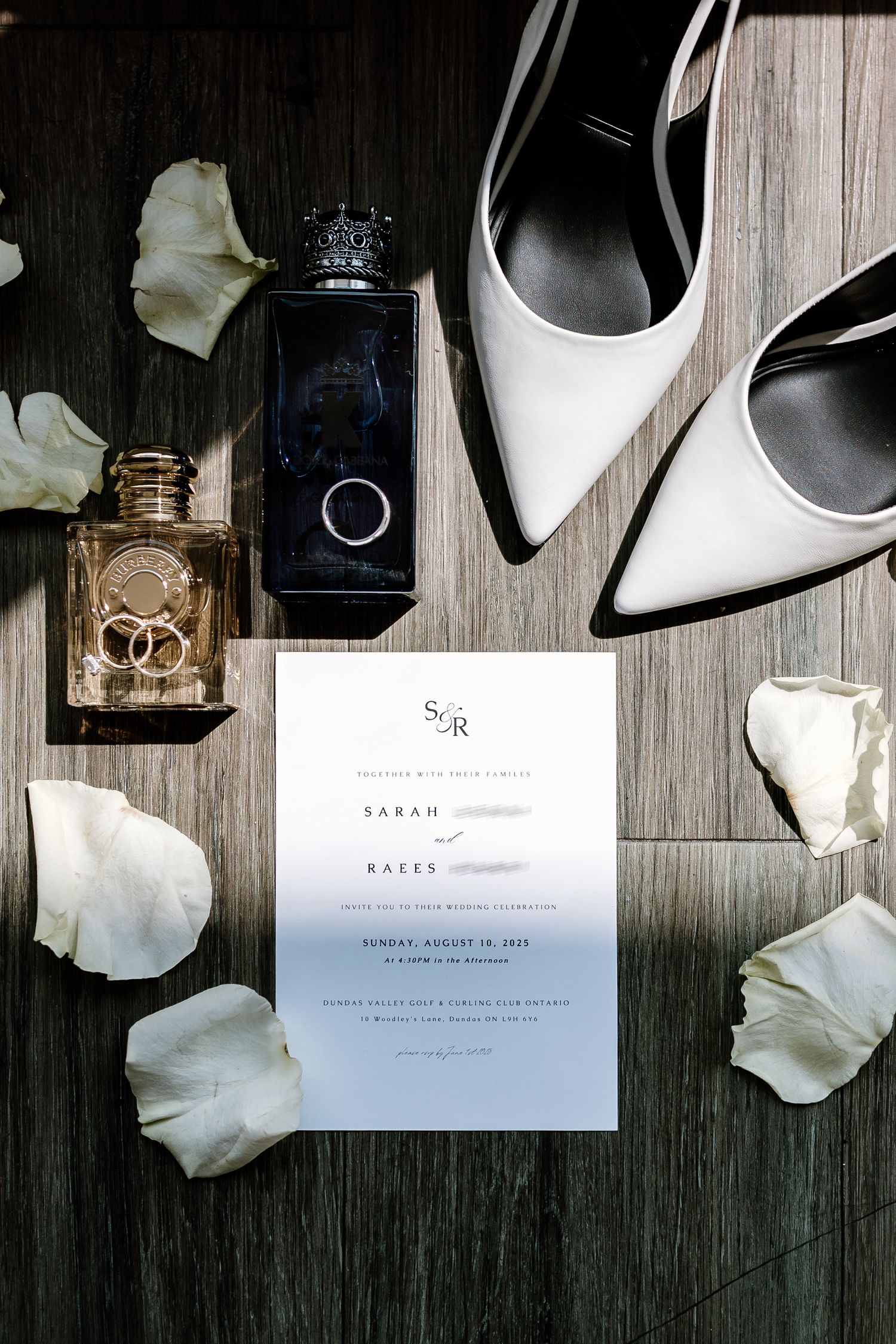 Wedding flat lay with white shoes, perfume bottles, invitation and flower petals.