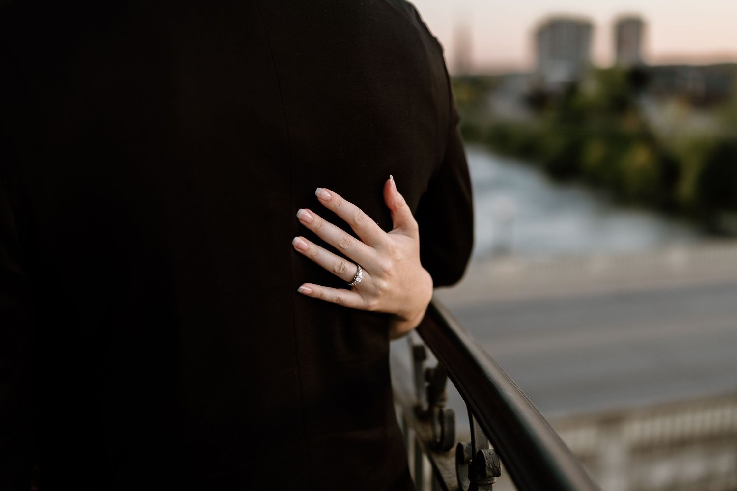 Silhouetted couple sharing tender moment at dusk with city backdrop.