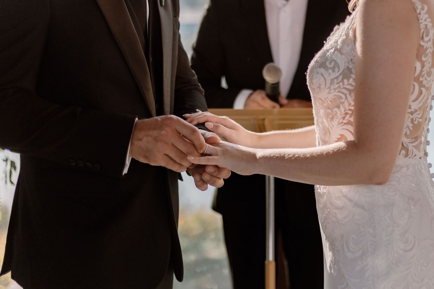 Intimate wedding ceremony moment with couple exchanging vows by sunlit windows.