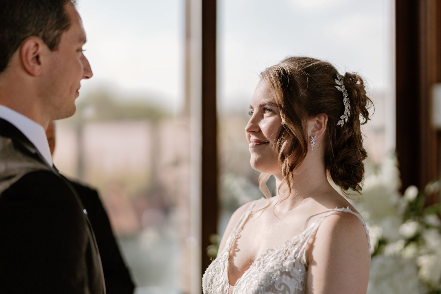 Wedding couple exchanges vows in front of an officiant with natural light streaming through windows.