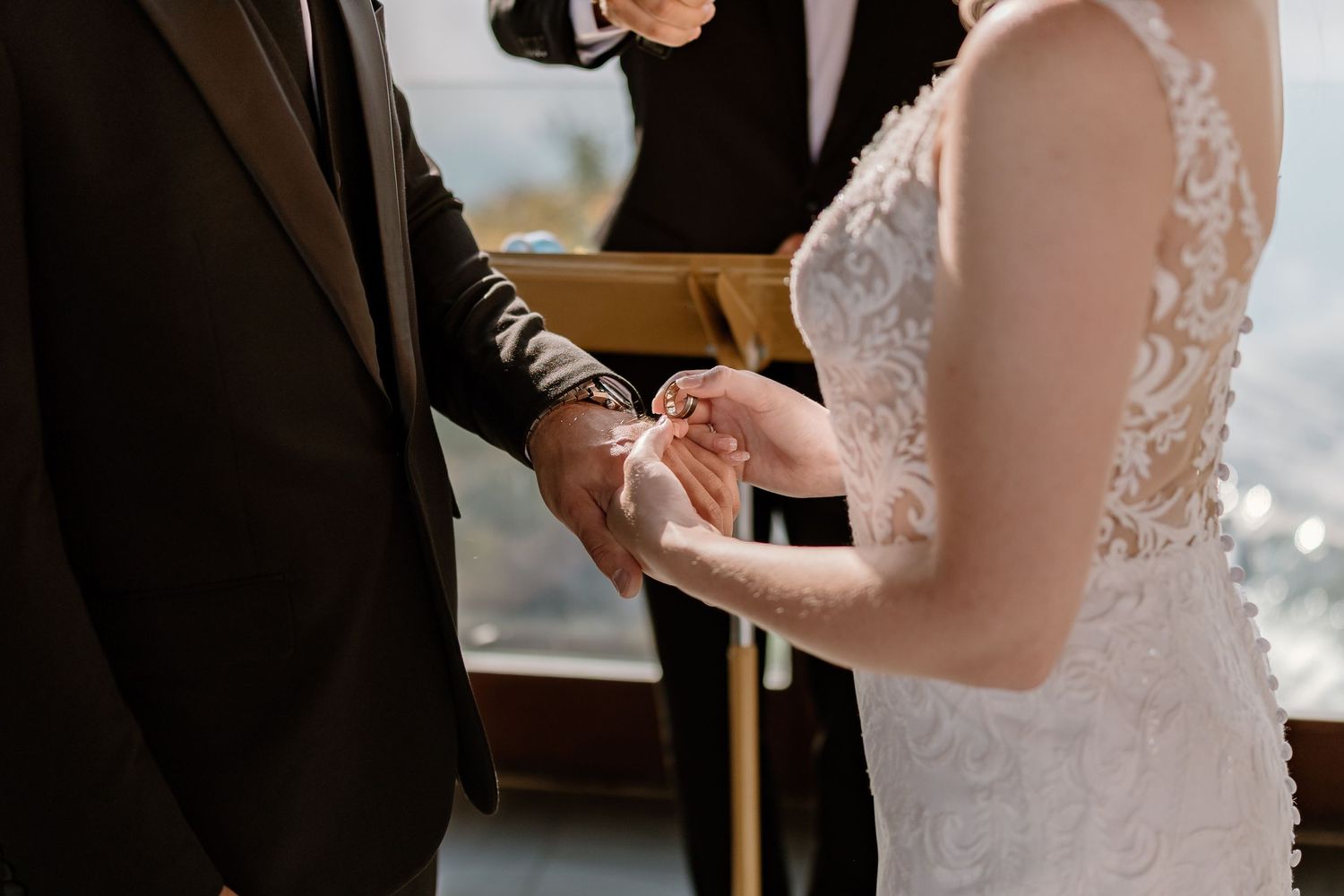 Couple exchanges rings during intimate wedding ceremony with natural light streaming through windows.